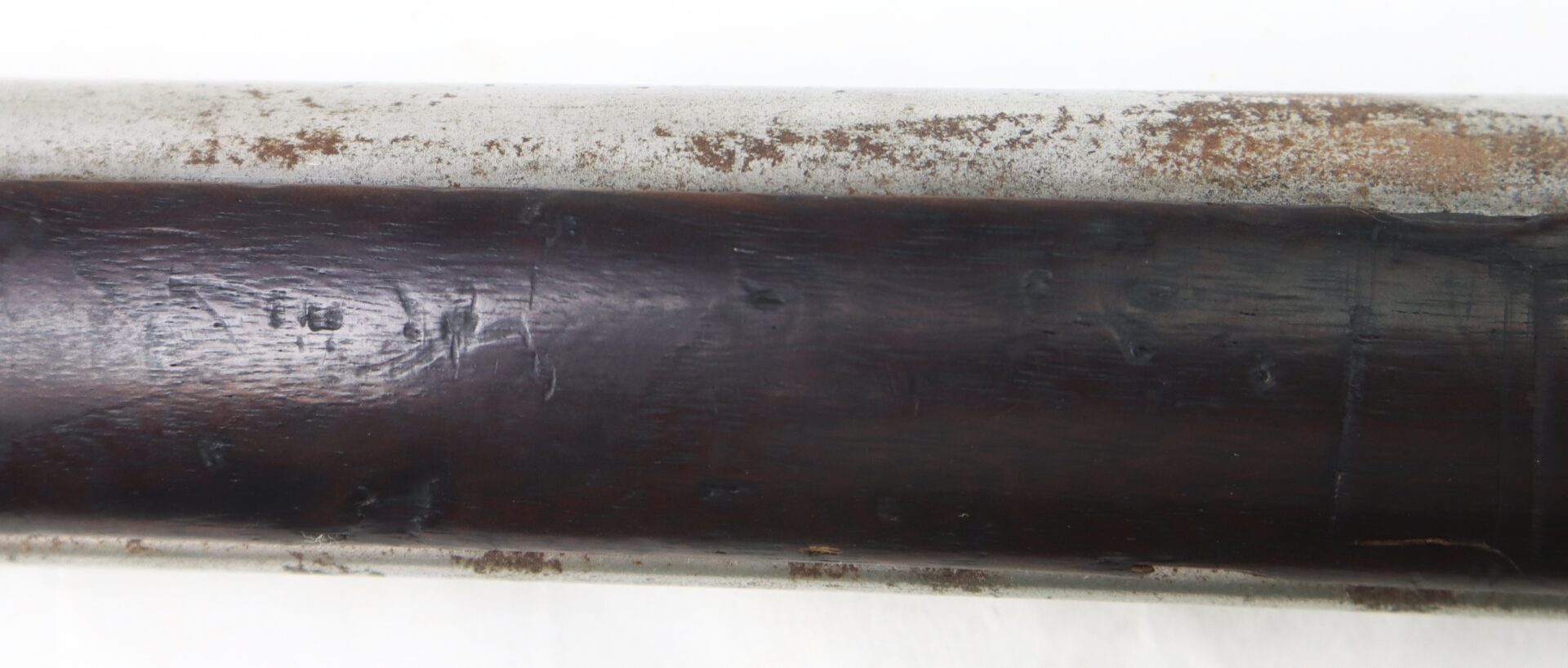Close-up of a weathered metal tube and dark wood with scratches and areas of surface rust.