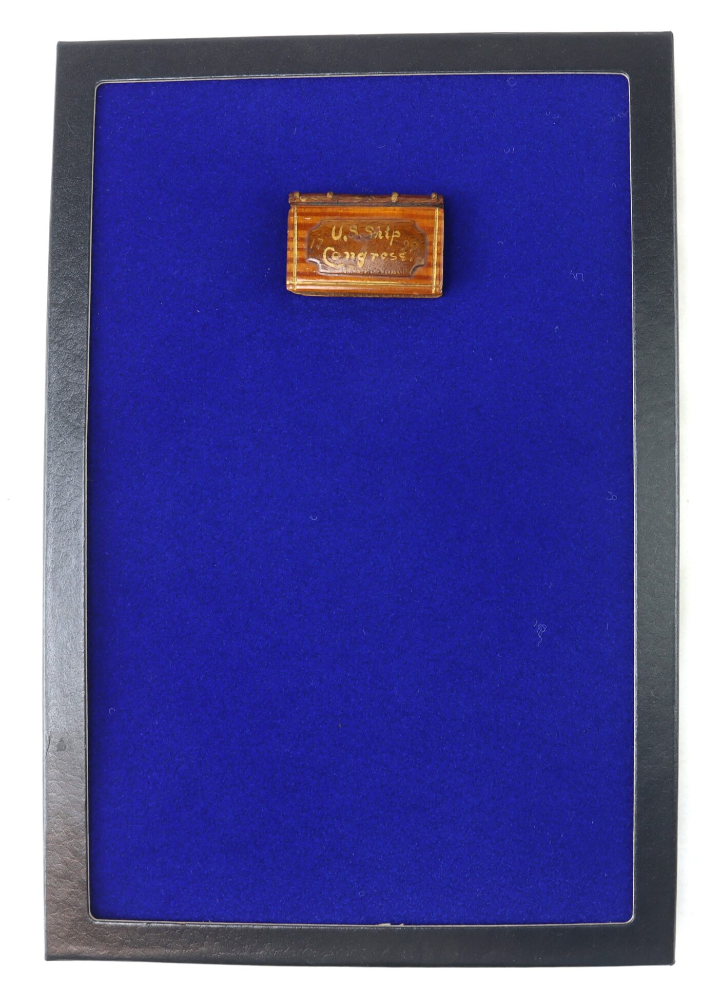 A rectangular display case with a bright blue interior background and a small labeled wooden box mounted near the top.