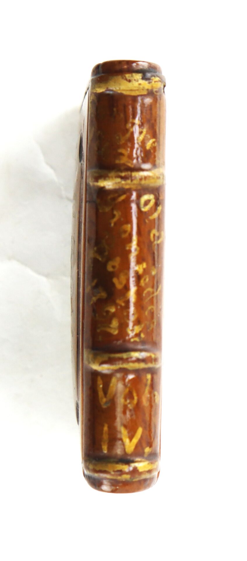 Close-up of the spine of an old, worn brown leather book with faded gold lettering and the Roman numerals "VI" and "IV" visible at the bottom.