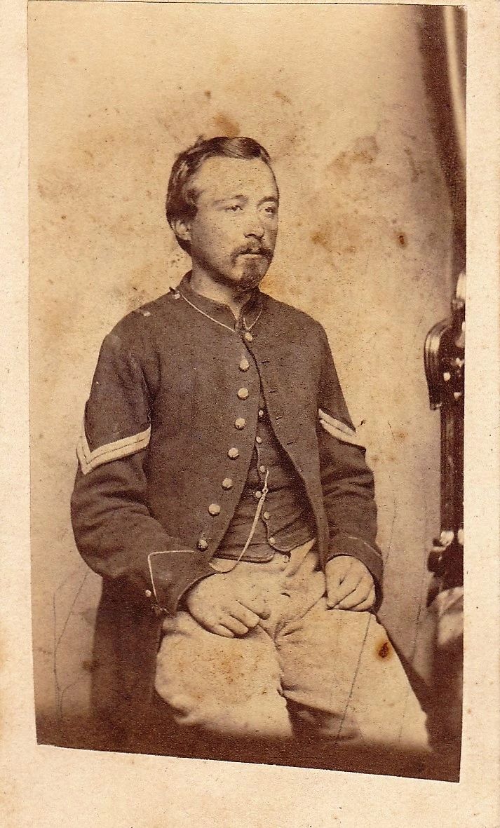 Sepia-toned photograph of a seated man in a Civil War-era uniform with chevrons on his sleeves, identified as Company "B" 7th Pennsylvania Volunteer Reserve Corps. Studio portrait, plain backdrop. / SOLD.