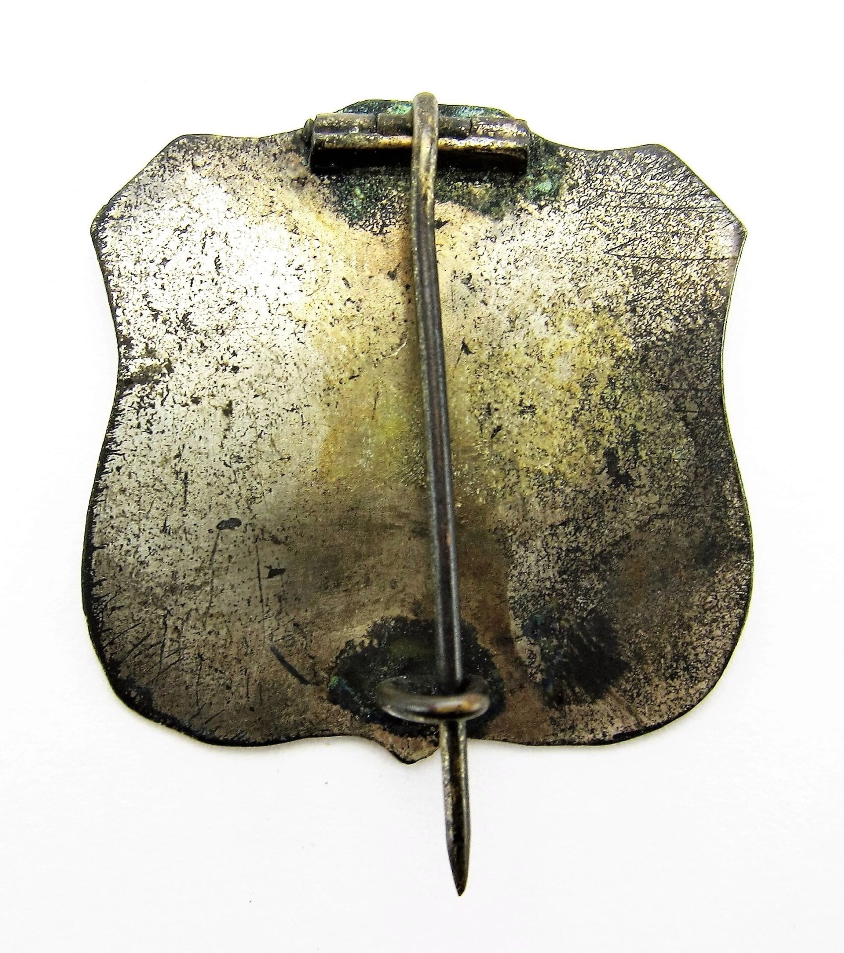 A tarnished 9th Army Corps Badge featuring a simple clasp and pin mechanism, photographed from the back against a white background.