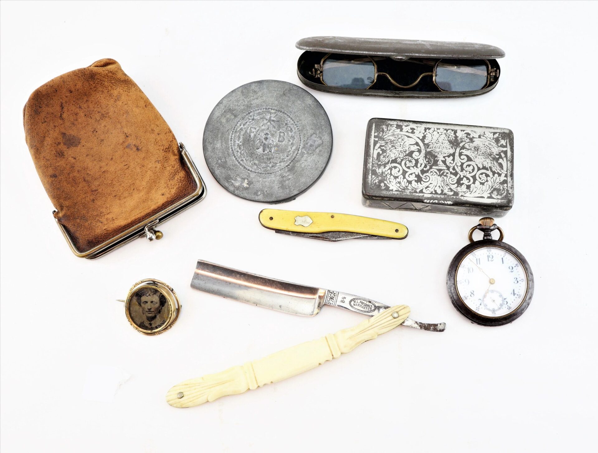 Personal effects of Civil War surgeon Dr. Seth L. Sprague, including a coin purse, round tin, eyeglasses in case, metal box, pocket watch, folding knife, straight razor, letter opener, and photo locket. / SOLD.