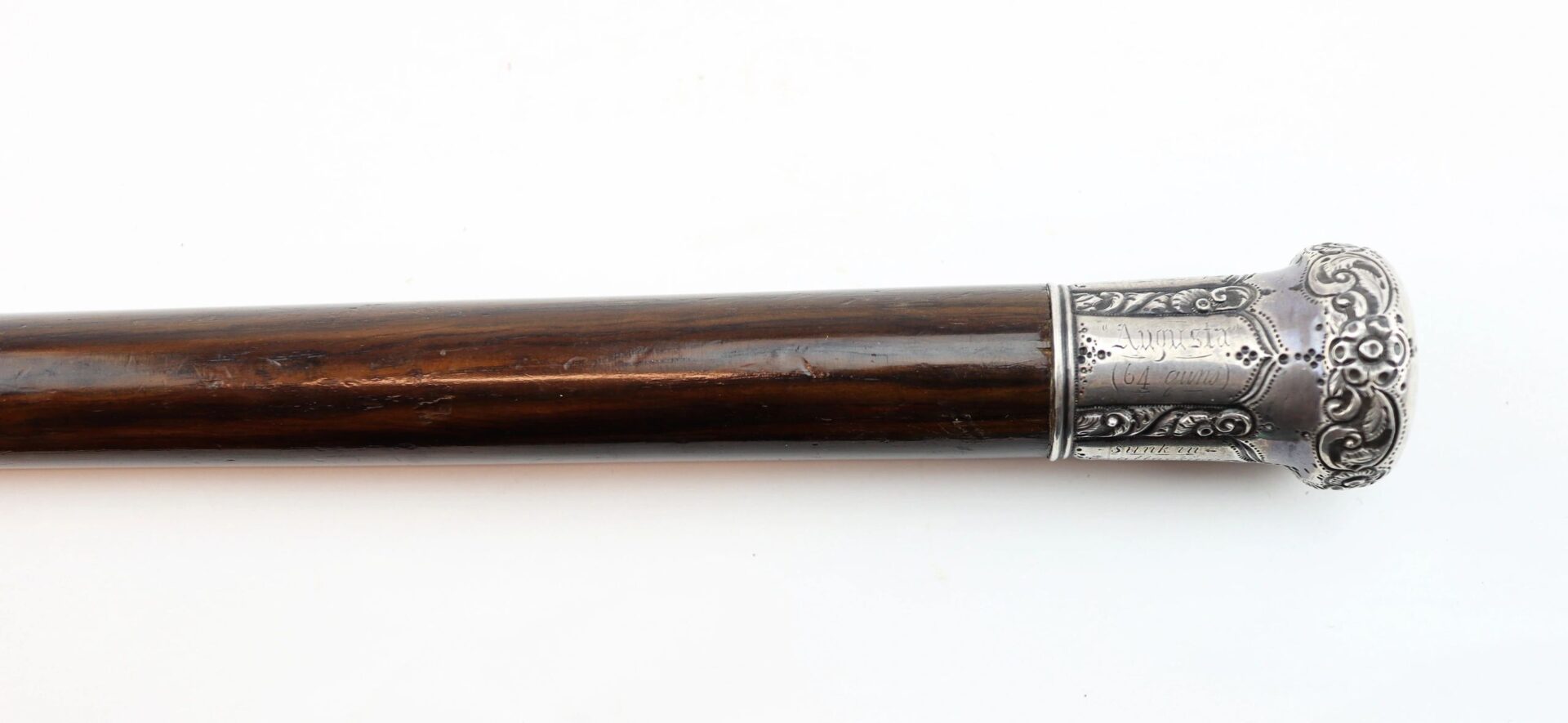 A walking cane crafted from Revolutionary War battleship wood with an ornate silver handle featuring detailed engravings, shown on a white background.