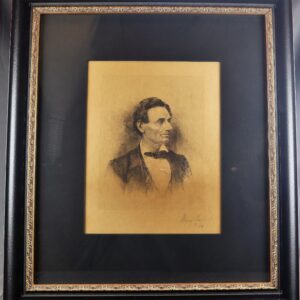 Framed portrait sketch of Abraham Lincoln in a bow tie and suit, displayed with a wide black mat and ornate gold-trimmed frame.