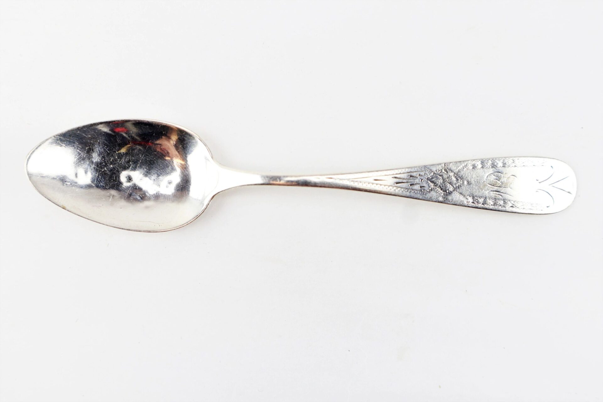 A Civil War Silver Teaspoon with an ornate, engraved floral handle is displayed against a plain white background.