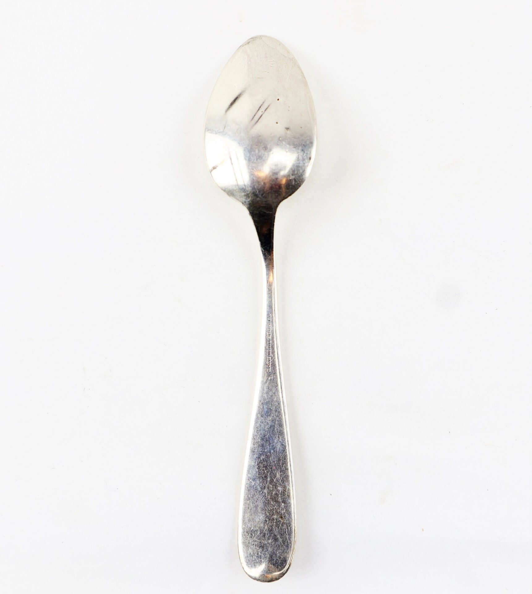 A Civil War Silver Teaspoon with a gently worn, reflective surface rests on a plain white background.