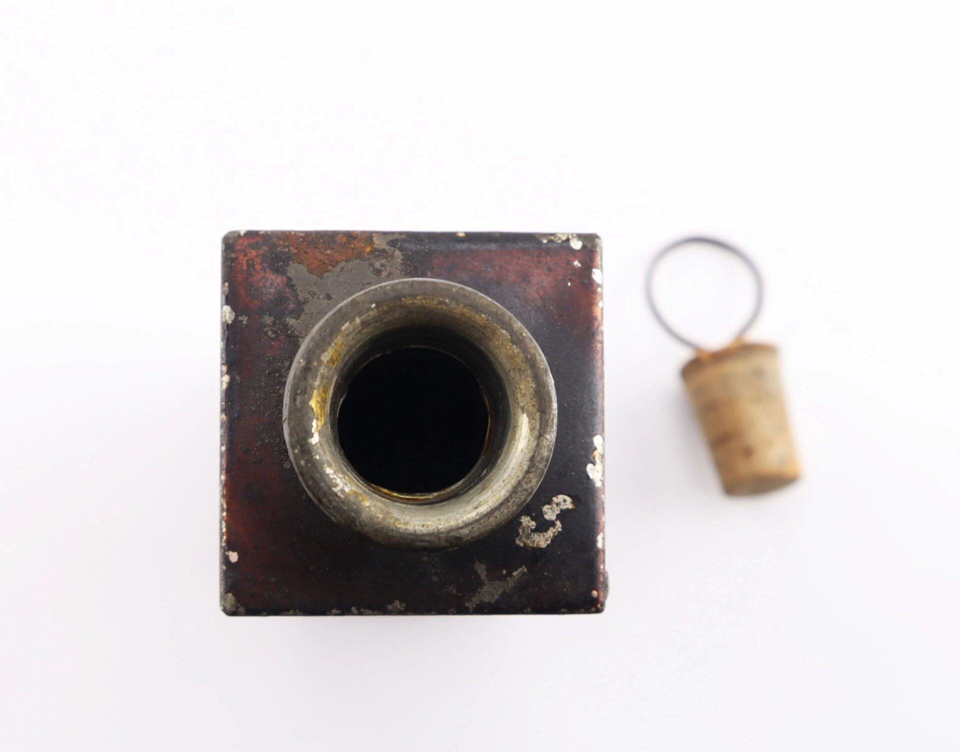 Top view of a Civil War Medical Tin with a circular opening, next to a cork stopper with a metal ring, displayed on a white background.
