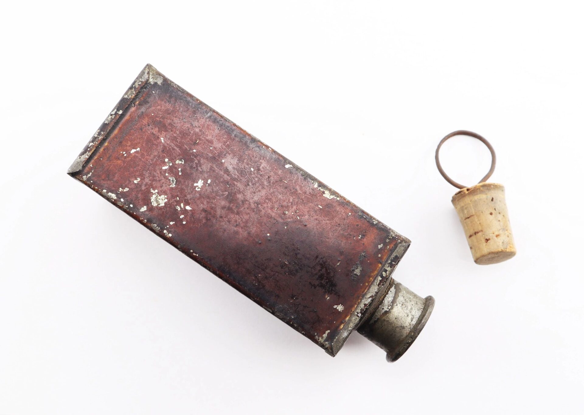 A rectangular Civil War Medical Tin with a cork stopper lying beside it on a white background.