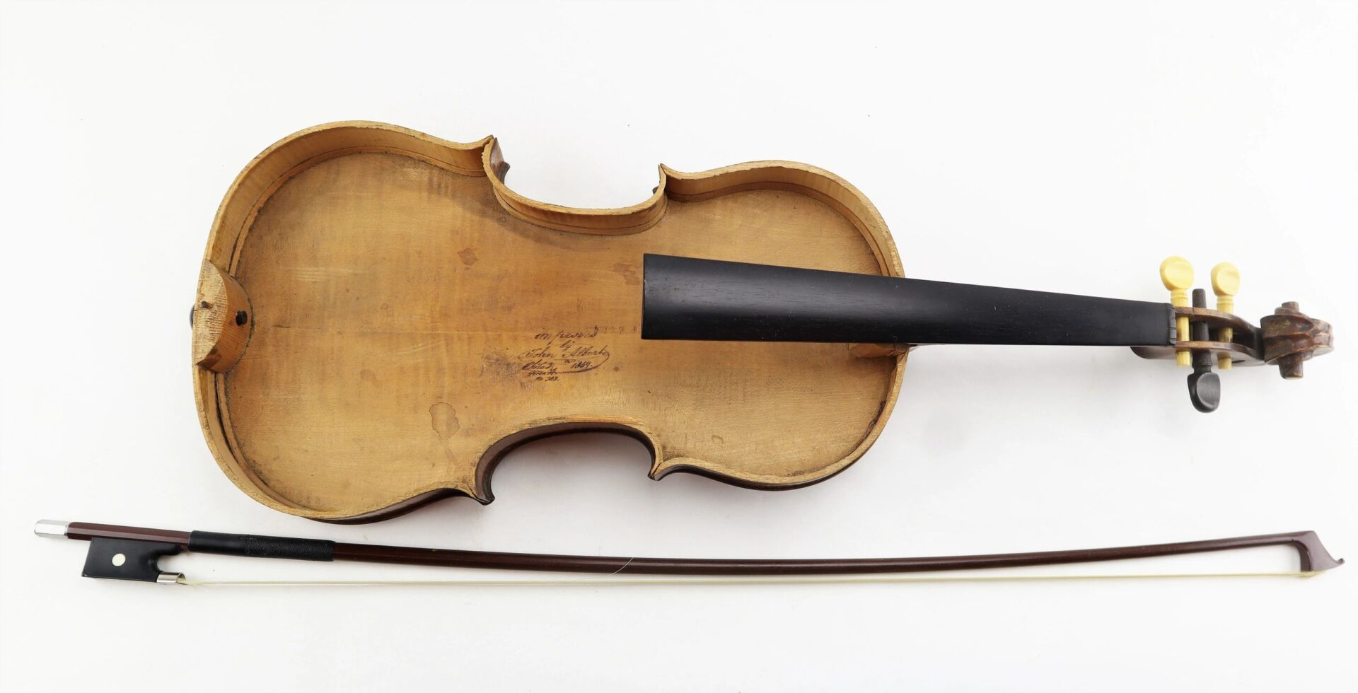 The Violin / Sold is pictured without its top plate next to a bow, set against a white background.