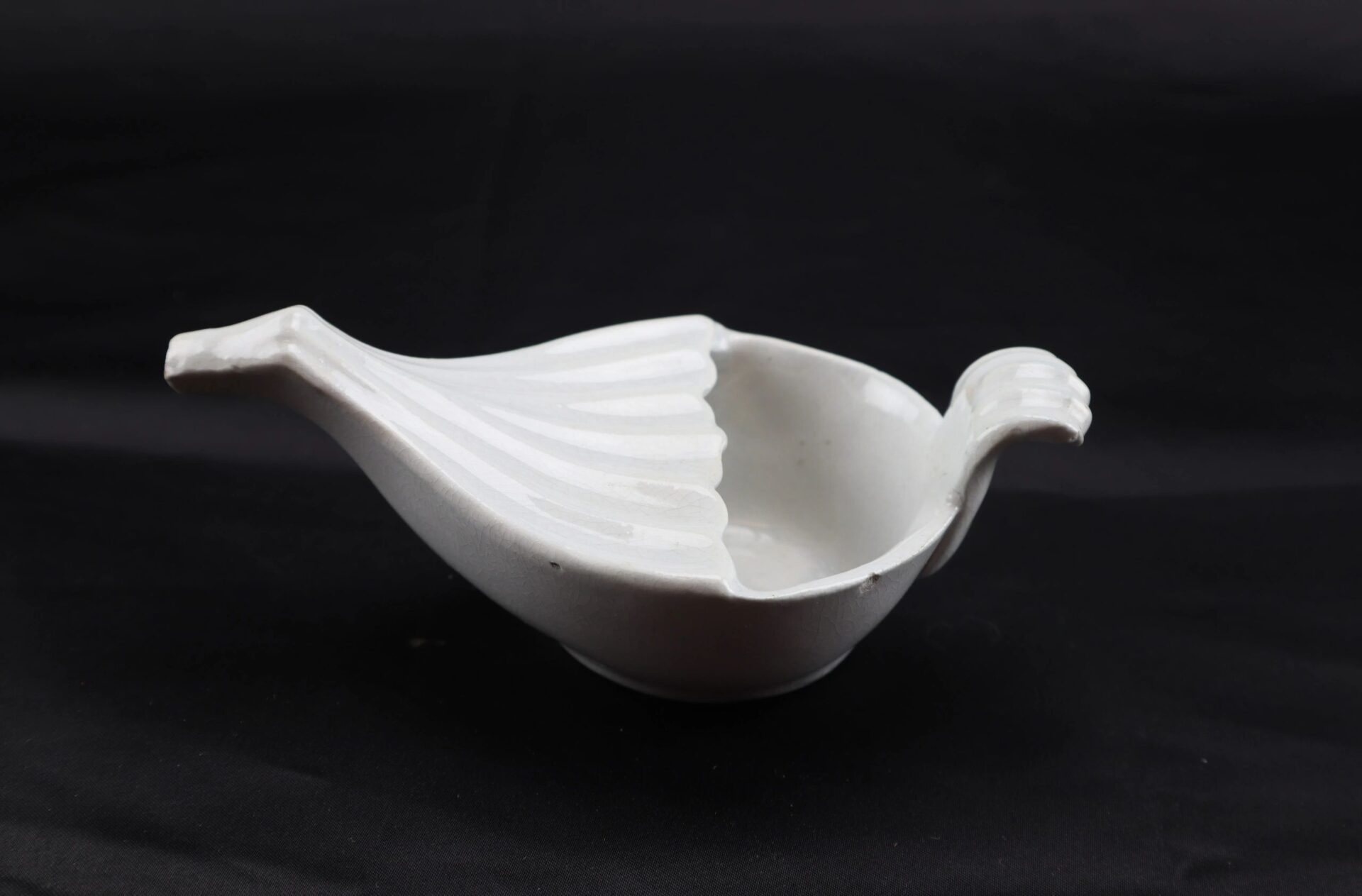 Invalid Feeder / SOLD: A white ceramic dish shaped like a bird, featuring a tail-like handle and small beak, displayed against a black background.