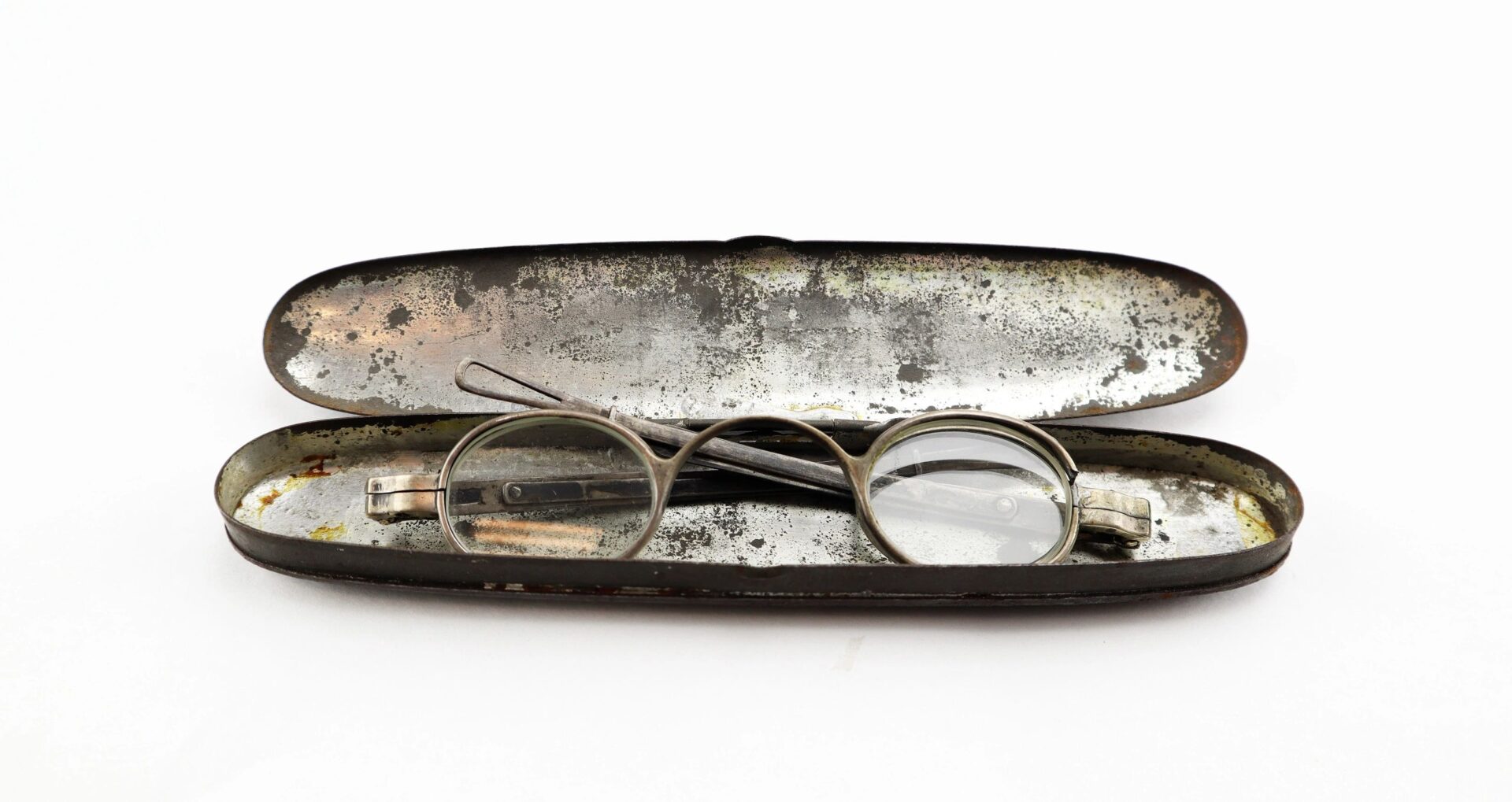 A pair of Civil War Eyeglasses with round metal frames rests inside an open, worn metal case against a white background.