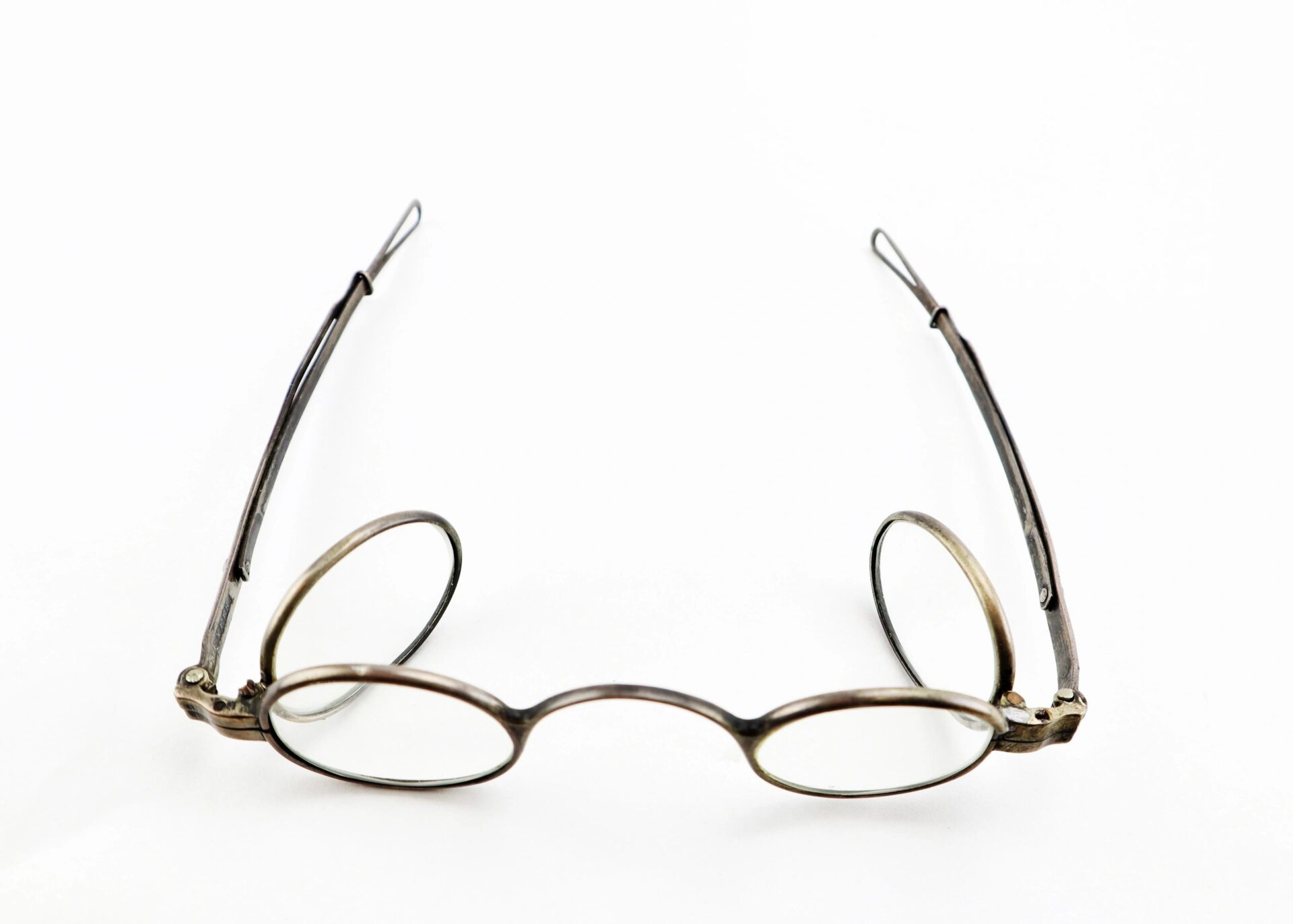 A pair of Civil War Eyeglasses with thin metal frames and an oval shape is displayed open on a white background.