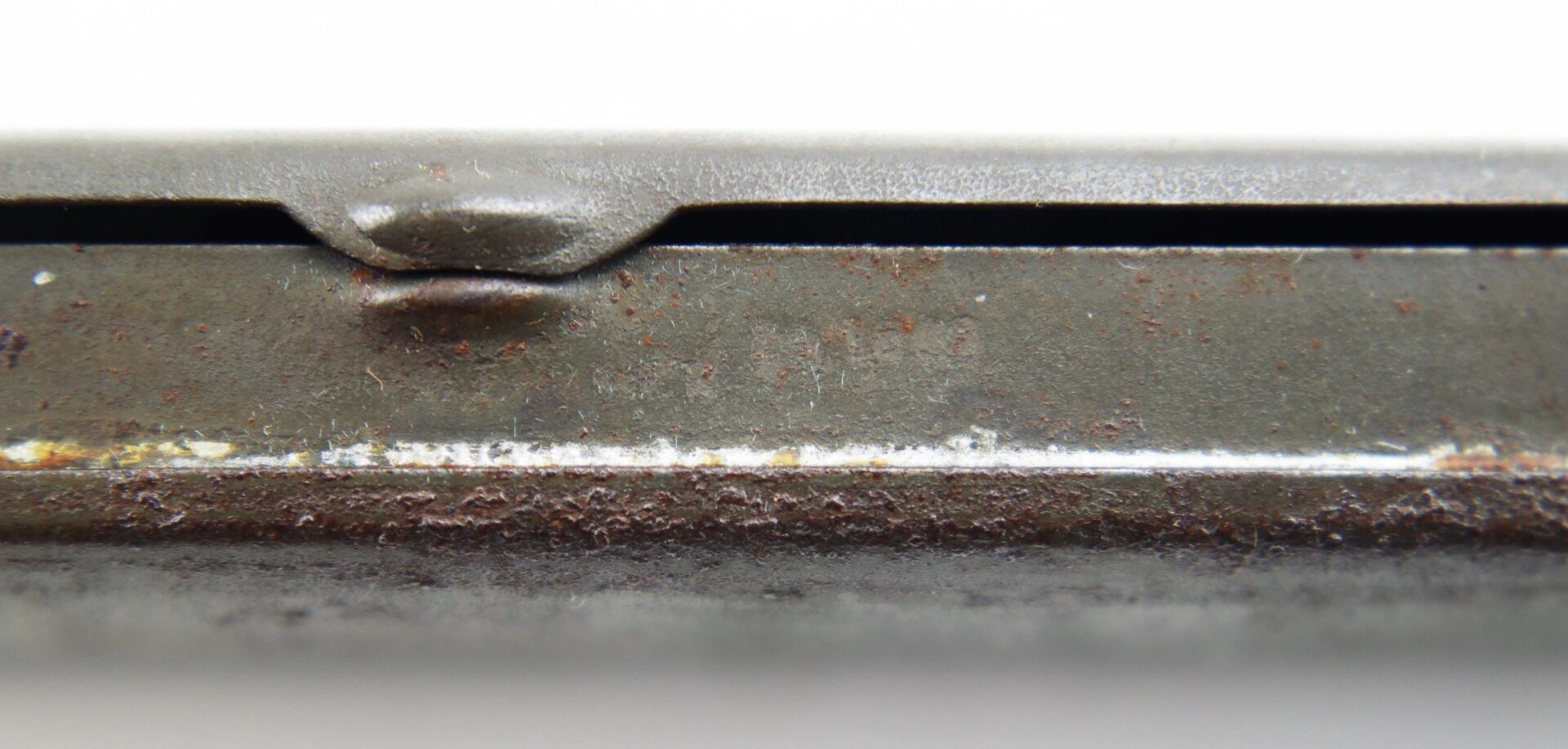 Close-up of Civil War Eyeglasses / SOLD showing a metal surface with visible rust, corrosion, and a small raised notch against a white background.