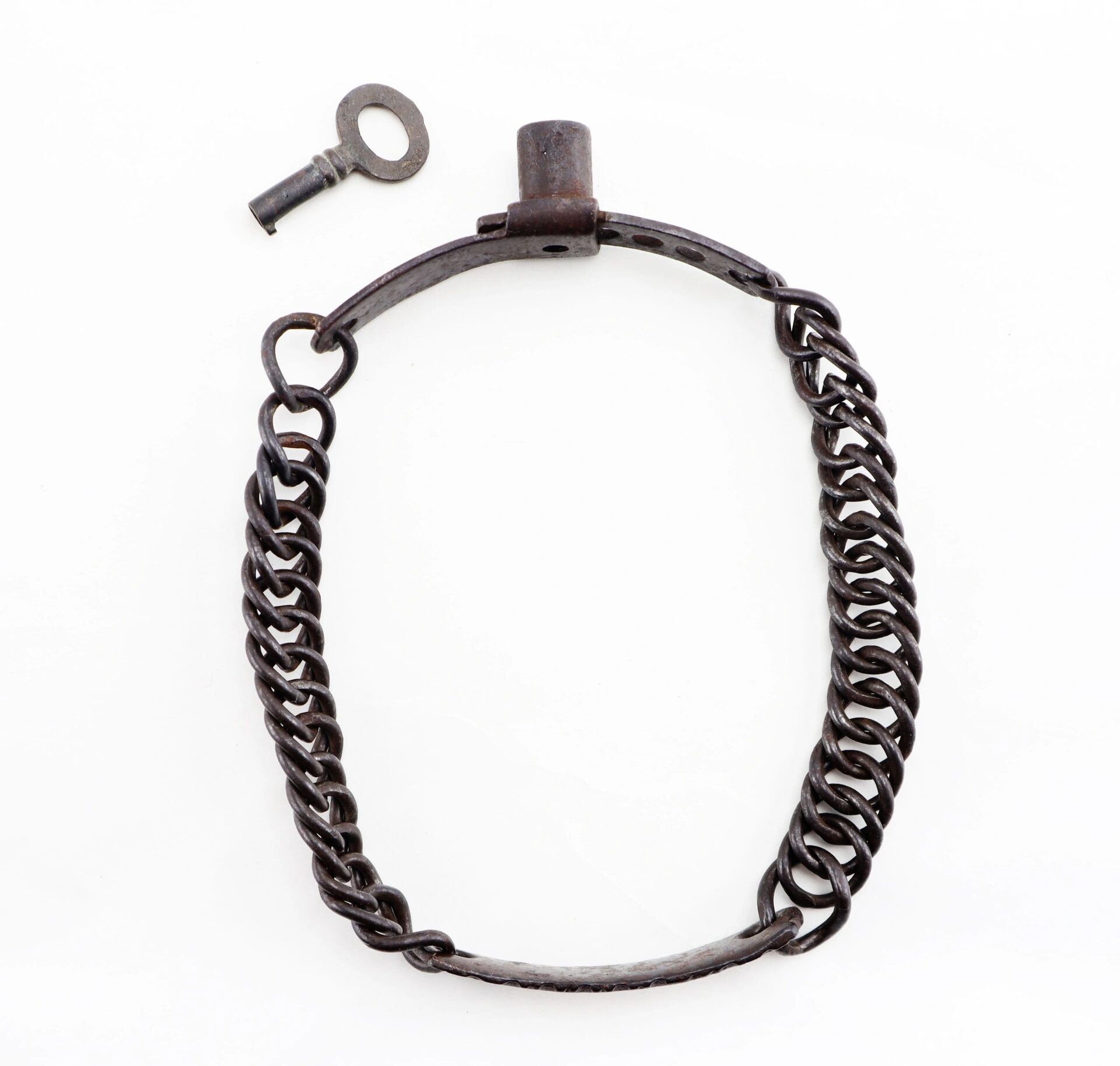 A Civil War dog/slave collar with a metal shackle, chain, and small key displayed on a white background.