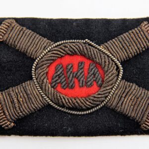 The A.H.A. Officer's Hat Insignia is a rectangular black fabric patch featuring two crossed metallic cannons and a red oval center with "AHA" in black lettering.