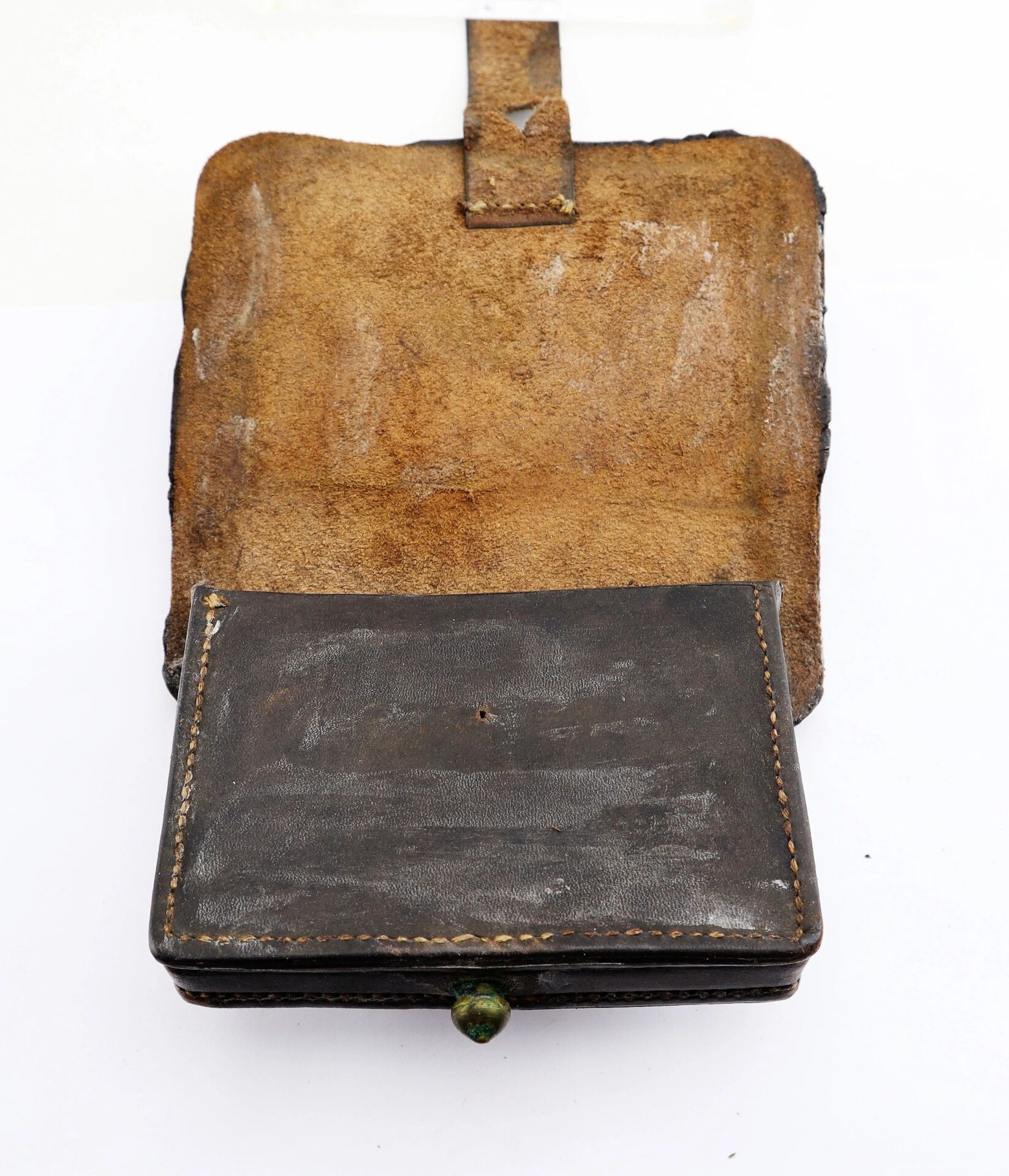 A Civil War Pistol Cartridge Box, crafted from worn brown leather with a flap open to show a rectangular compartment, visible stitching, and a small green button clasp.
