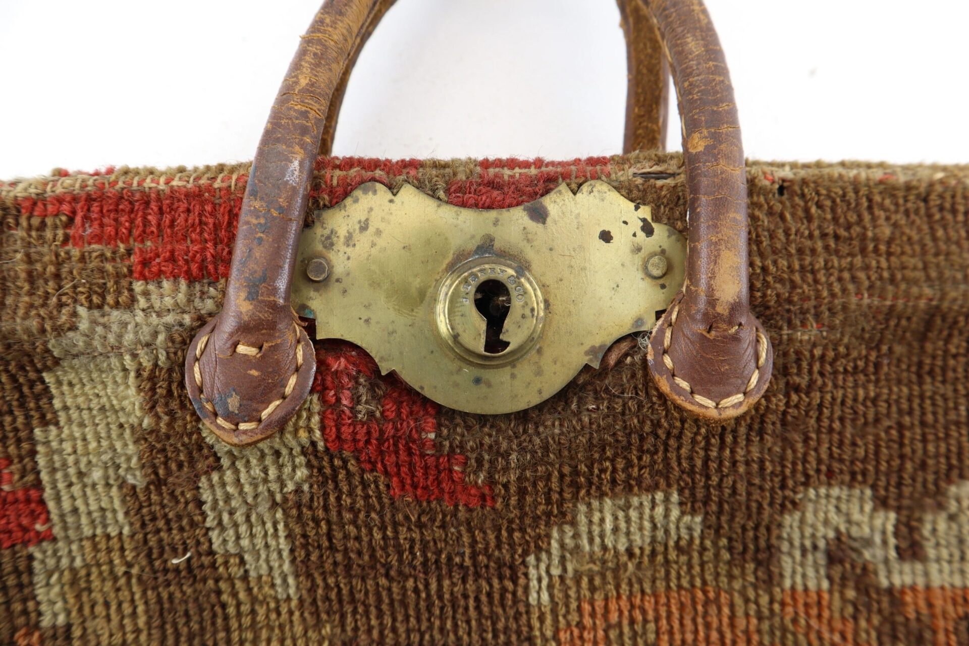 Close-up of a Civil War “Carpet Bag” with a worn leather handle and a tarnished brass lock plate featuring a keyhole. Sold.