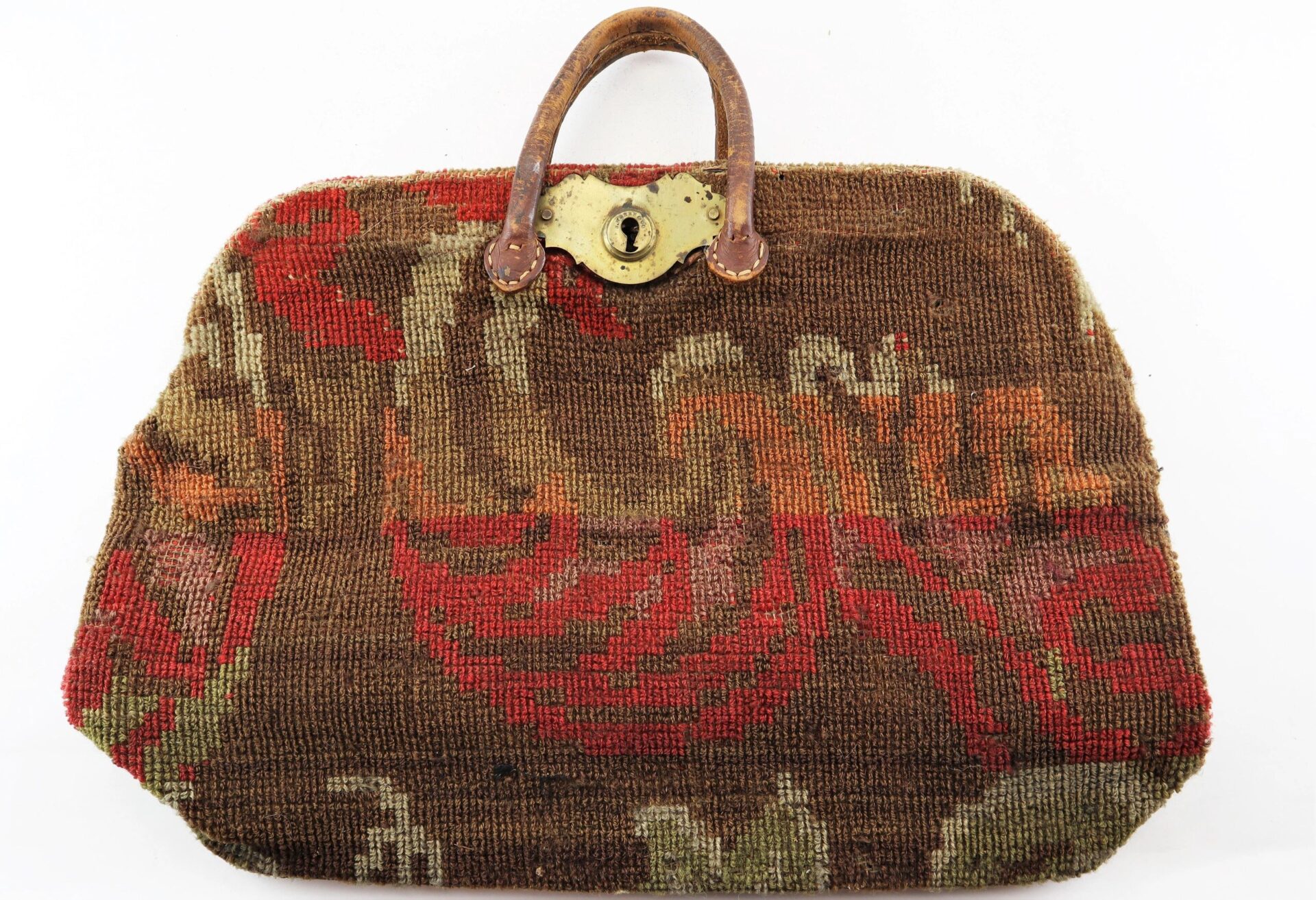 The Civil War “Carpet Bag” features a floral tapestry pattern in red, brown, and green, with a brass clasp and brown handle. Sold.