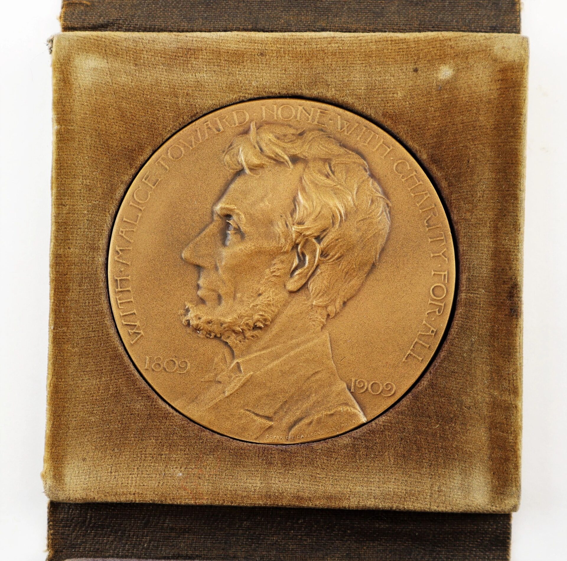 Abraham Lincoln Centennial Medal featuring Lincoln’s profile, “With malice toward none, with charity for all,” and the years 1809–1909, displayed on velvet. / Sold.