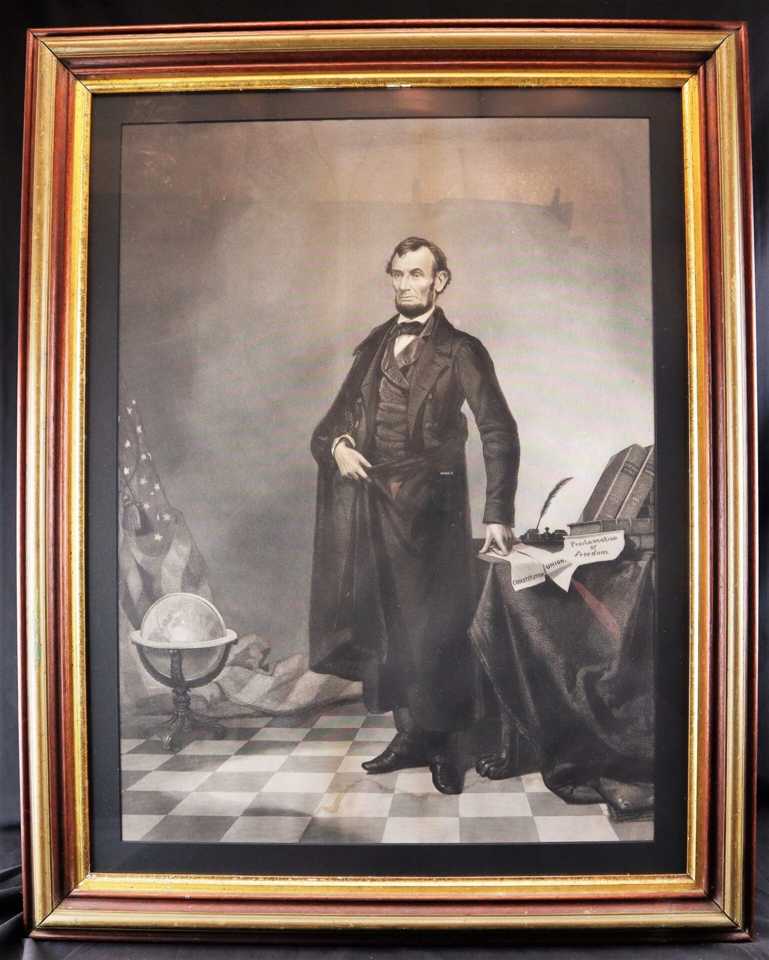 Framed black-and-white portrait titled "Abraham Lincoln / SOLD," featuring Abraham Lincoln standing by a table with books, papers, an inkwell, and a globe in the background.