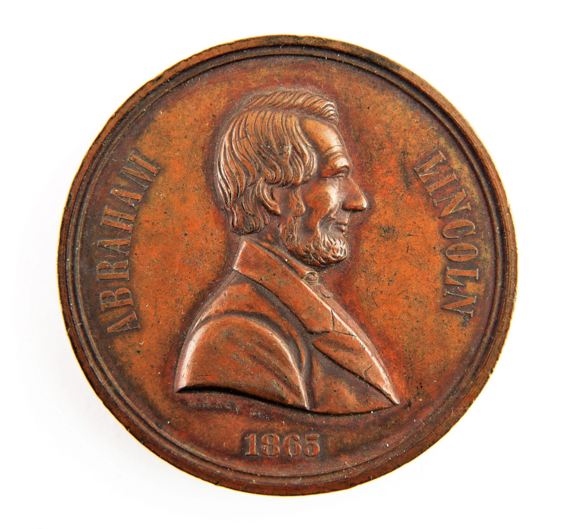 A bronze Lincoln 1865 Assassination Medal featuring Abraham Lincoln’s profile in relief, with his name and the year 1865 inscribed.