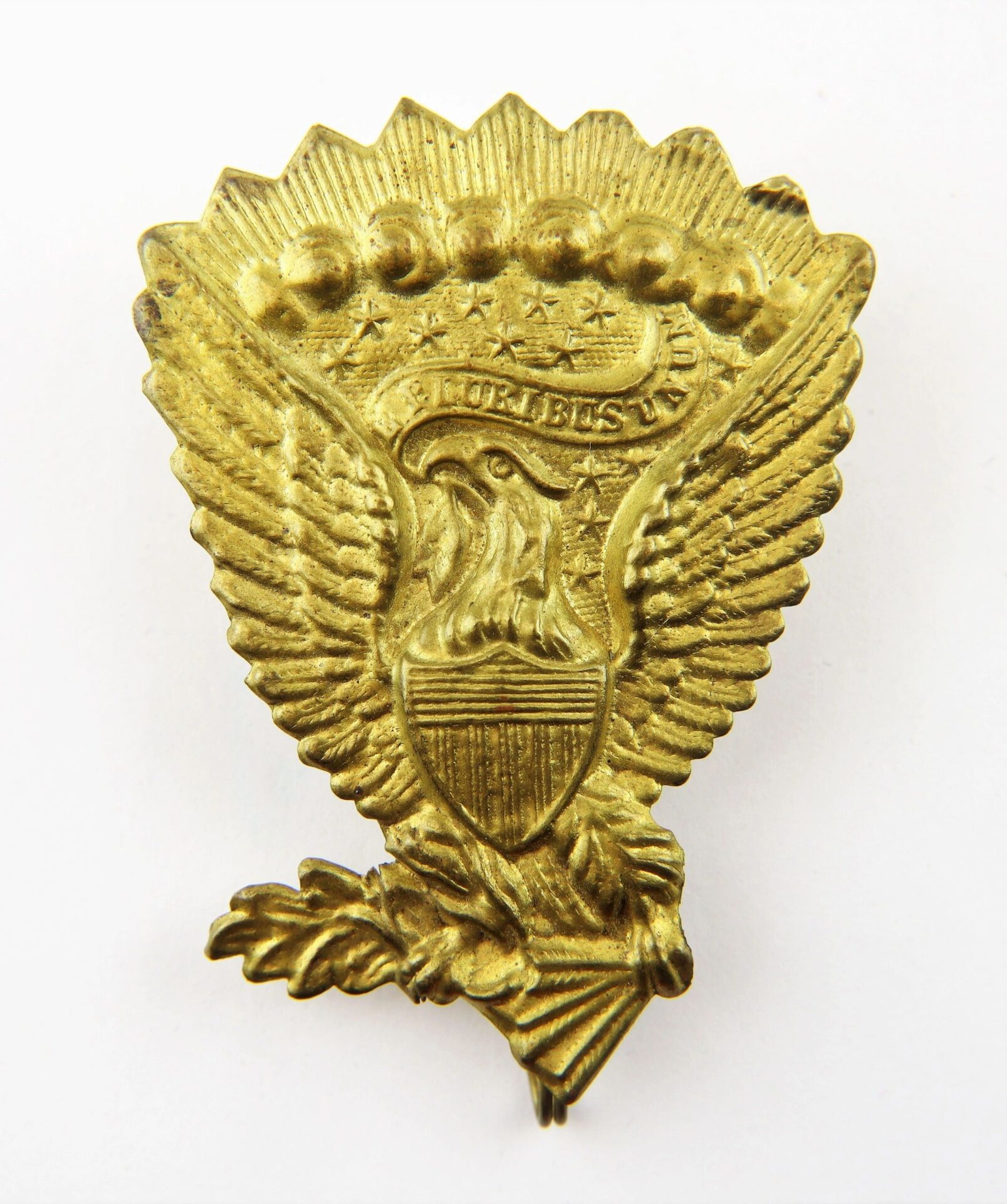 A brass "Jeff Davis" Hardee Hat insignia featuring a stylized eagle with a shield, stars above its head, and a banner reading "E Pluribus Unum.