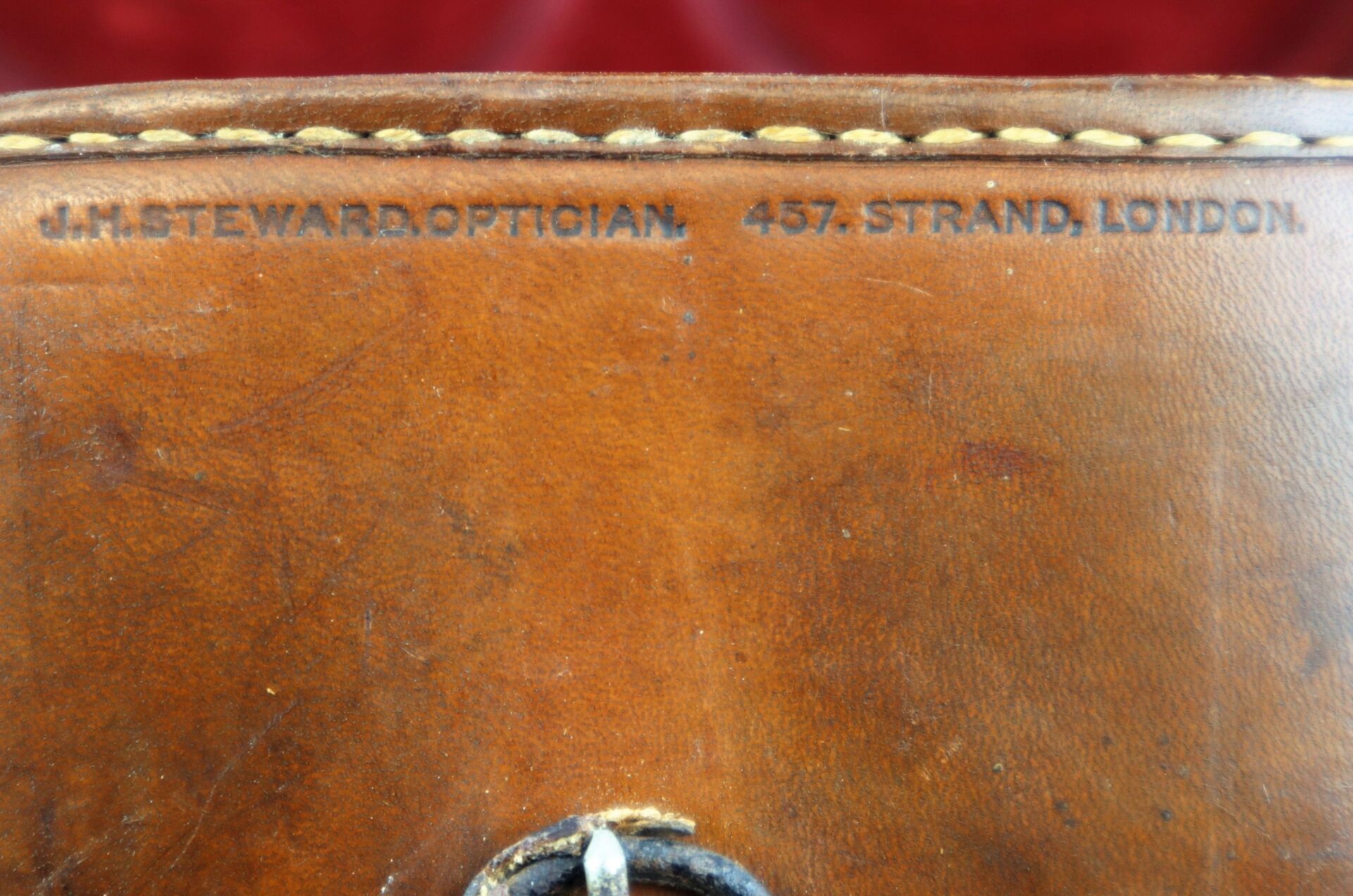Close-up of brown leather case for Civil War Field Glasses, with "J.H. Steward, Optician, 457. Strand, London" stamped near the stitched edge.
