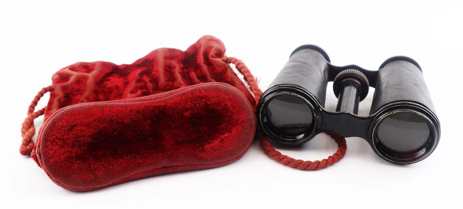 A pair of Civil War Era Field Glasses by Tiffany & Co. New York rests next to a red velvet carrying pouch on a white background.