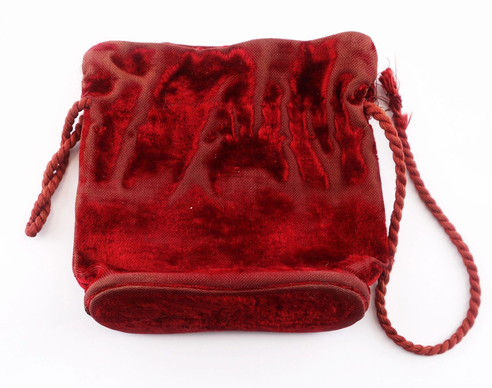 A pair of Civil War Era Field Glasses by Tiffany & Co. New York, shown in a red velvet drawstring pouch with a braided cord against a white background.