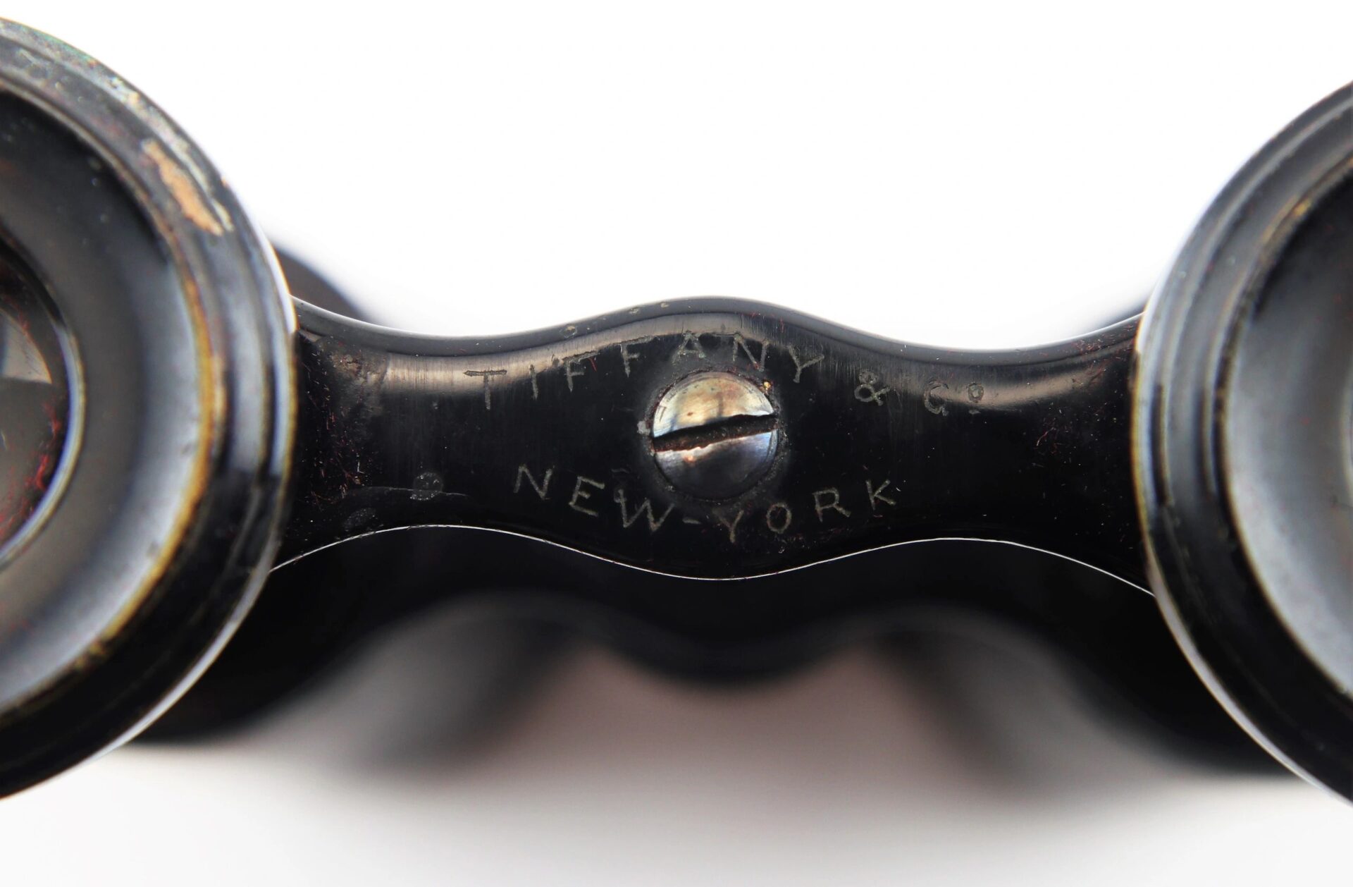 Close-up of Civil War Era Field Glasses by Tiffany & Co. New York, showing the engraved bridge, on a white background.