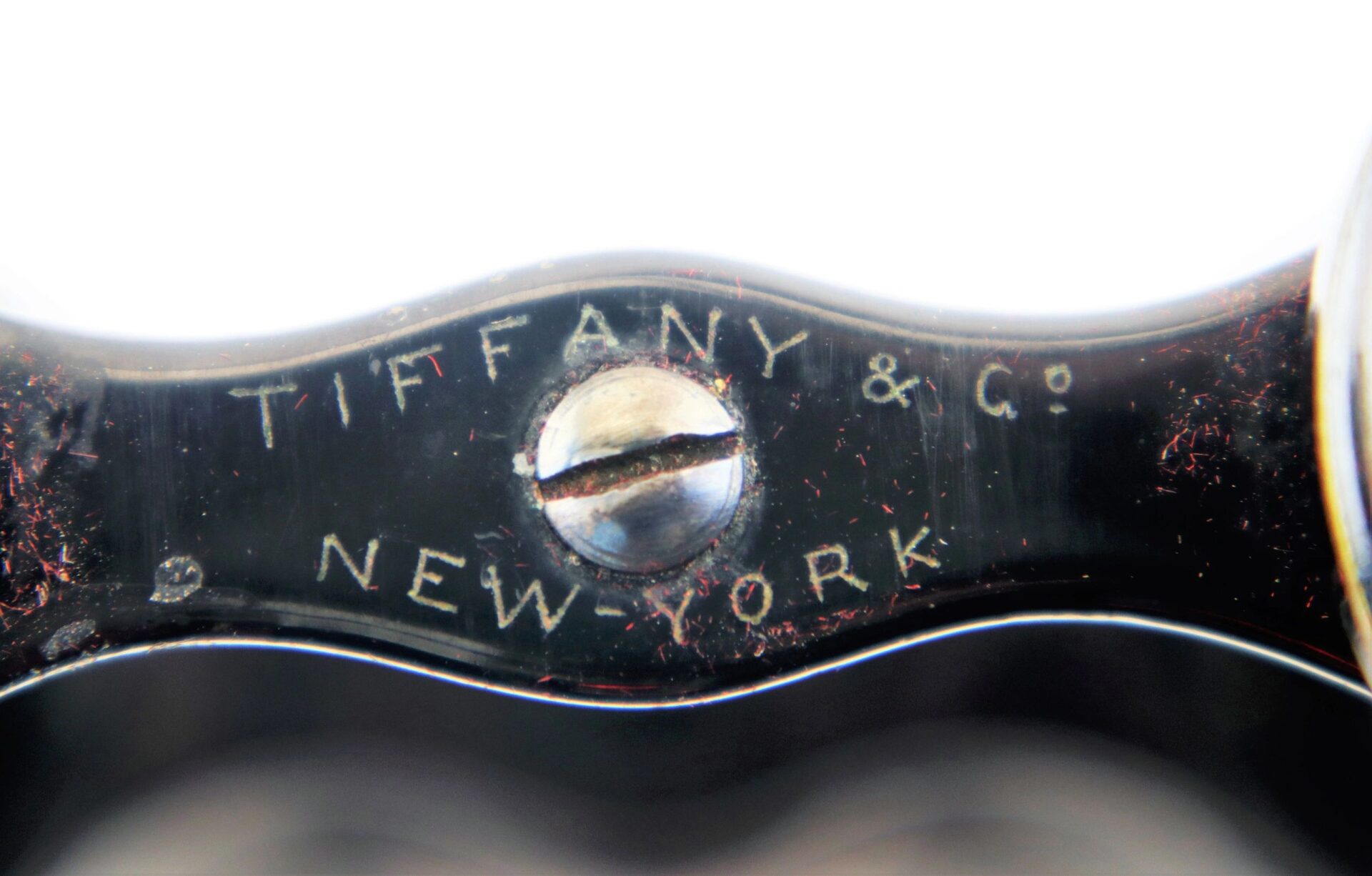 Close-up of Civil War Era Field Glasses engraved with "TIFFANY & CO. NEW YORK" around a central screw.
