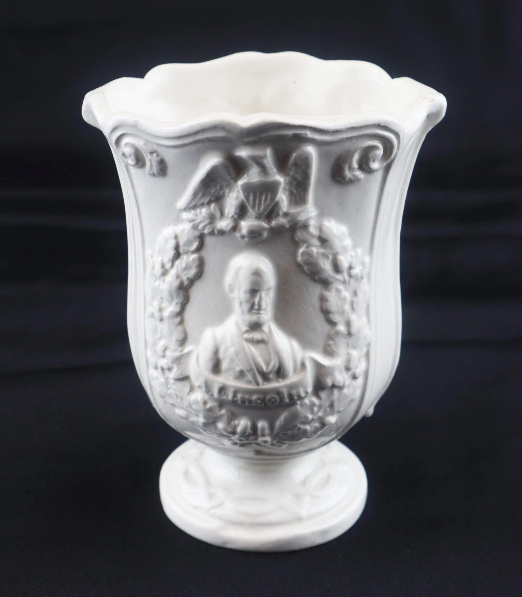 Civil War Vintage Abraham Lincoln Stoneware Vase featuring a relief of Lincoln in a suit, an eagle above, and decorative wreath detailing on the front.