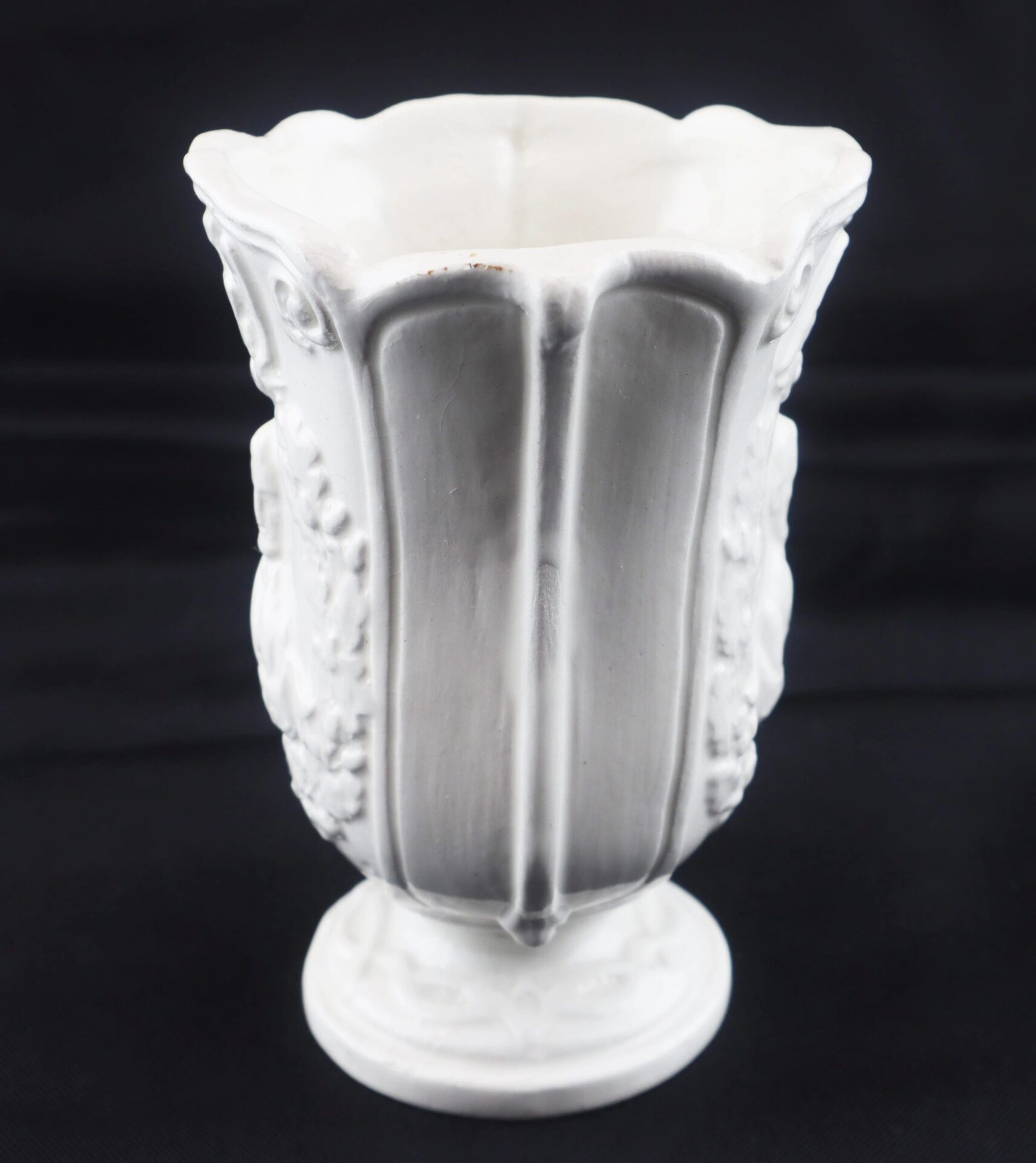 The Civil War Vintage Abraham Lincoln Stoneware Vase features a white ceramic finish with a fluted, scalloped rim and embossed floral patterns, displayed against a black background.