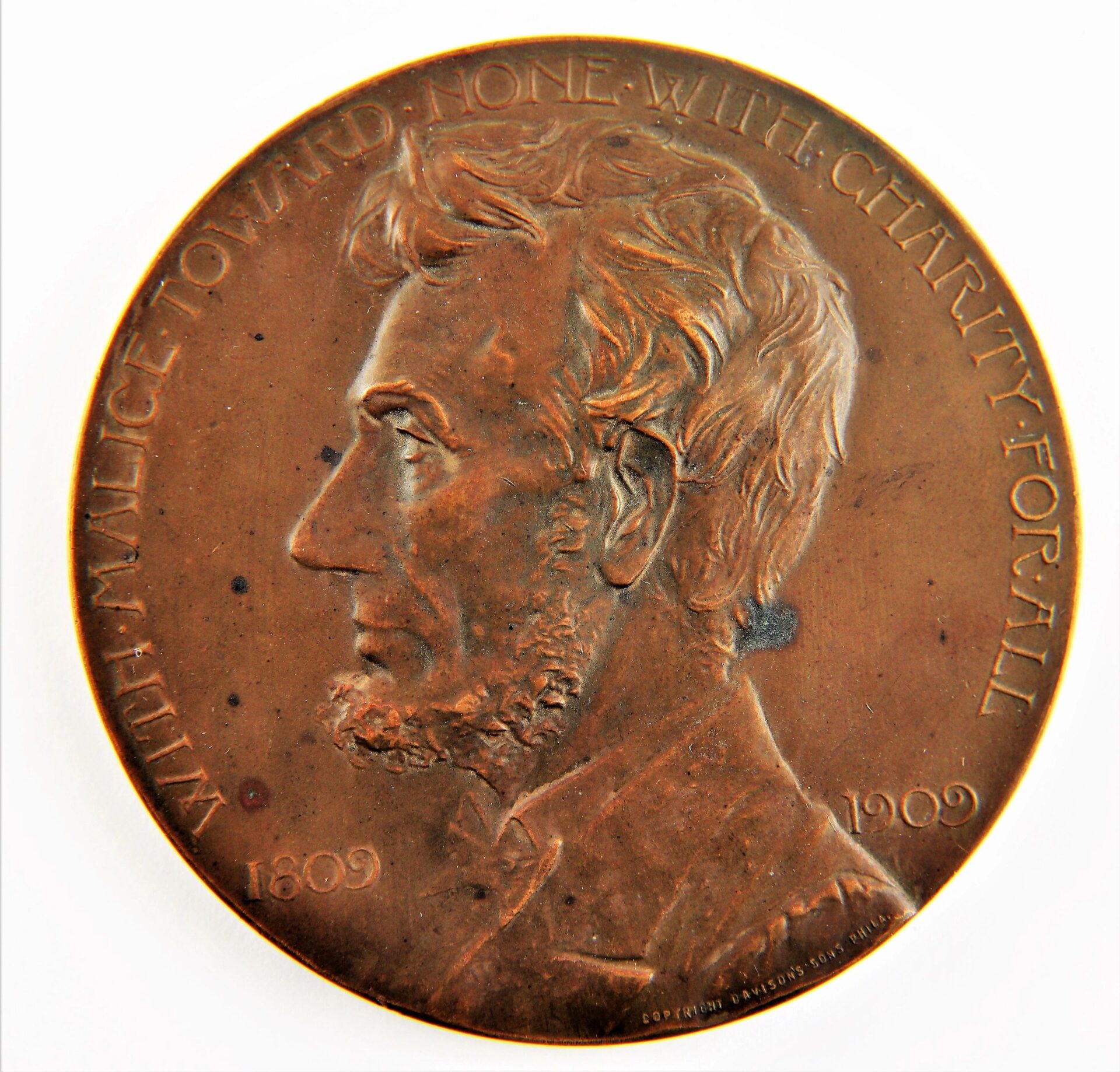 The Abraham Lincoln GAR Medallion features a left-facing profile of Lincoln and the inscription “With malice toward none, with charity for all, 1809 1909” around the edge.