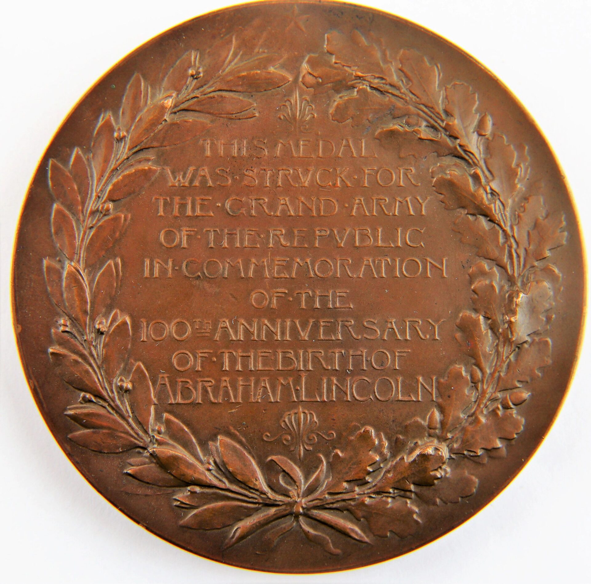A bronze Abraham Lincoln GAR Medallion commemorating his 100th birthday, featuring an inscribed tribute and laurel wreath design.