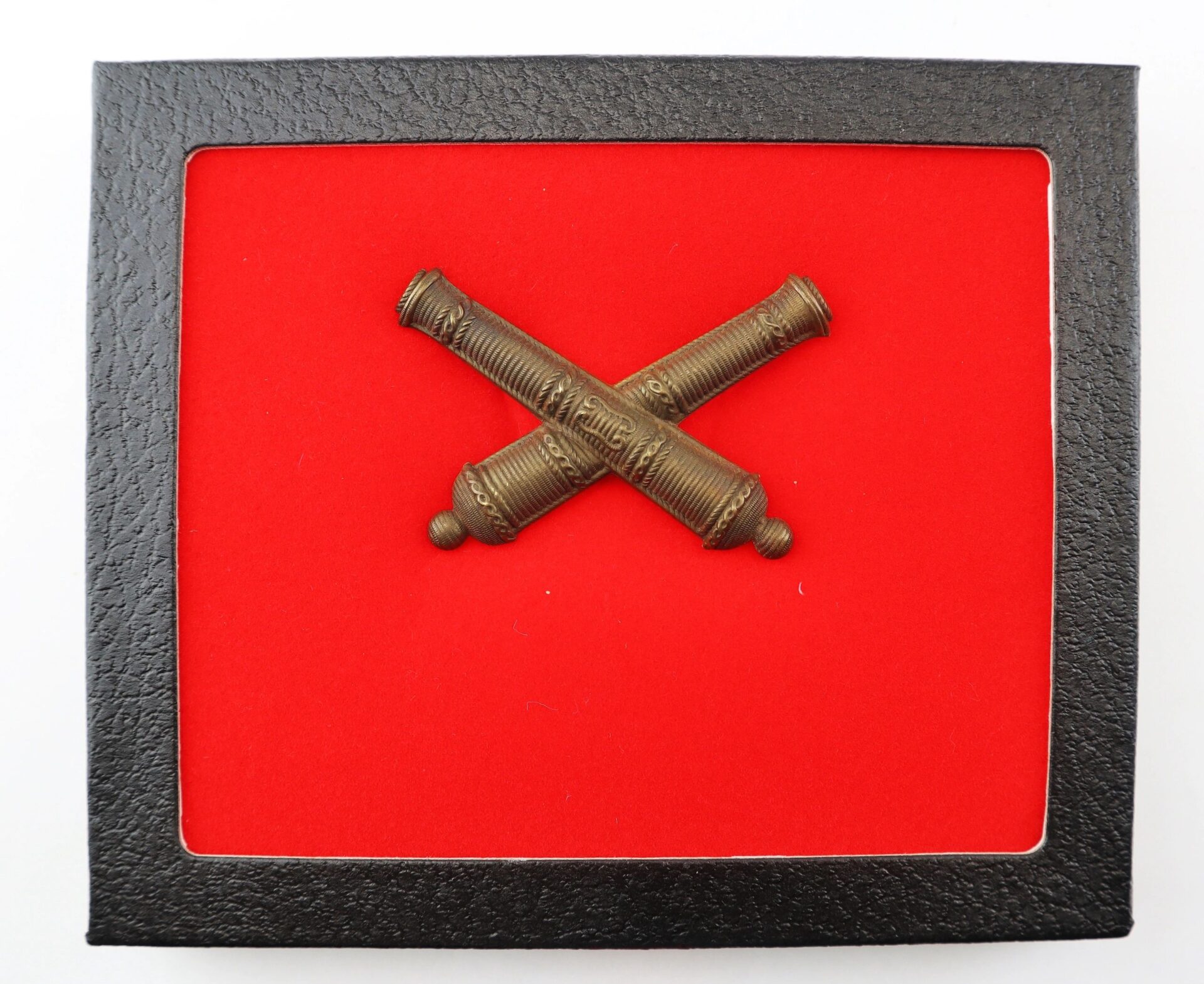The False Embroidered Civil War Officer’s Crossed Cannon Insignia features a pair of crossed brass cannons on a red background, set within a black rectangular frame.