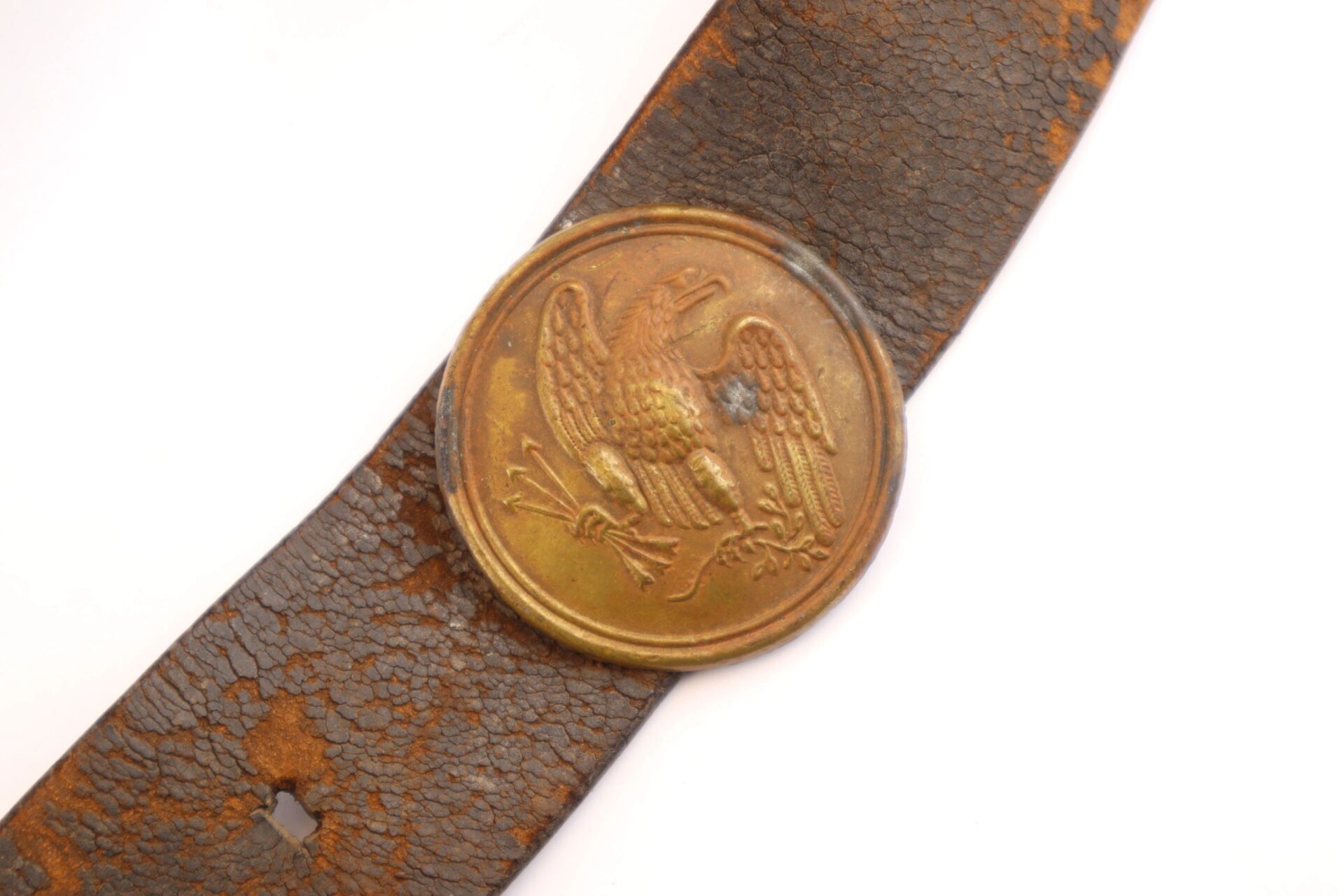 A Complete Cartridge Box, now sold, featuring a worn brown leather design with a round brass buckle depicting an eagle holding arrows.