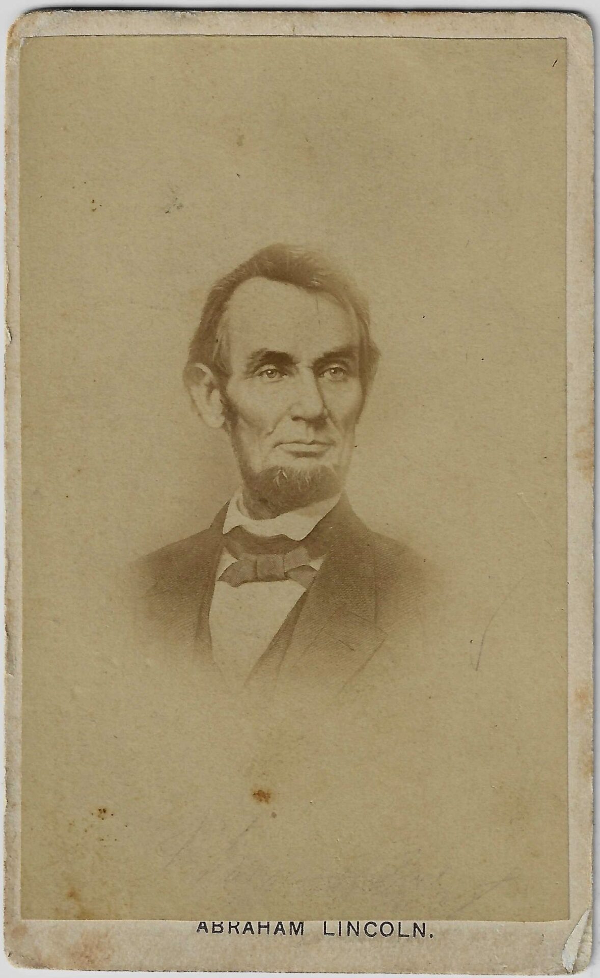 Sepia-toned CDV of Abraham Lincoln features a bearded man in a suit and bow tie, with "ABRAHAM LINCOLN." printed below. / SOLD.
