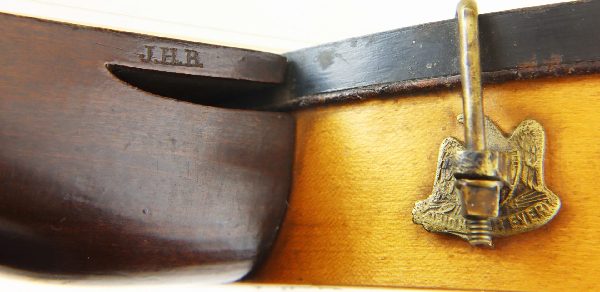 Close-up of a Civil War Era Banjo (SOLD) featuring a brass badge with an eagle and "RESERVE," and the initials "J.E.B." engraved on its wooden body.
