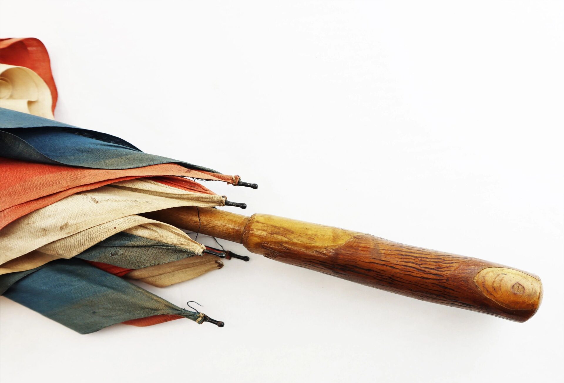 A closed Patriotic Parasol with a wooden handle and multicolored fabric on a white background.