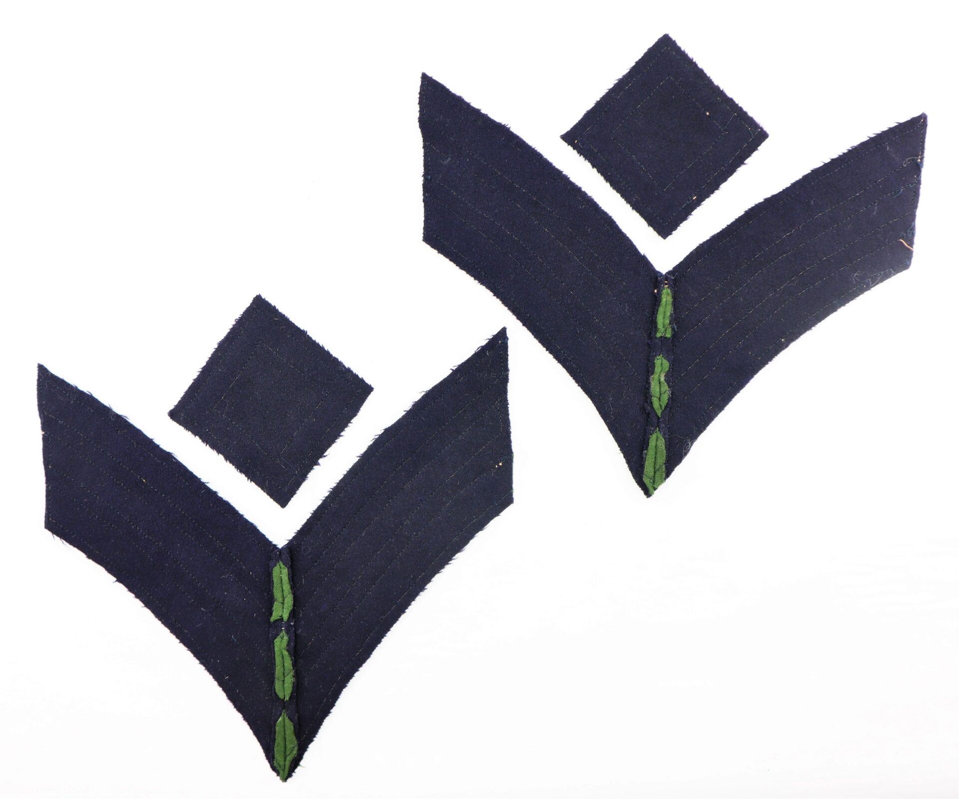 A pair of Civil War Rifleman/Sharpshooter Chevrons, navy blue fabric with V- and diamond shapes and green center stitching, are shown on a white background.