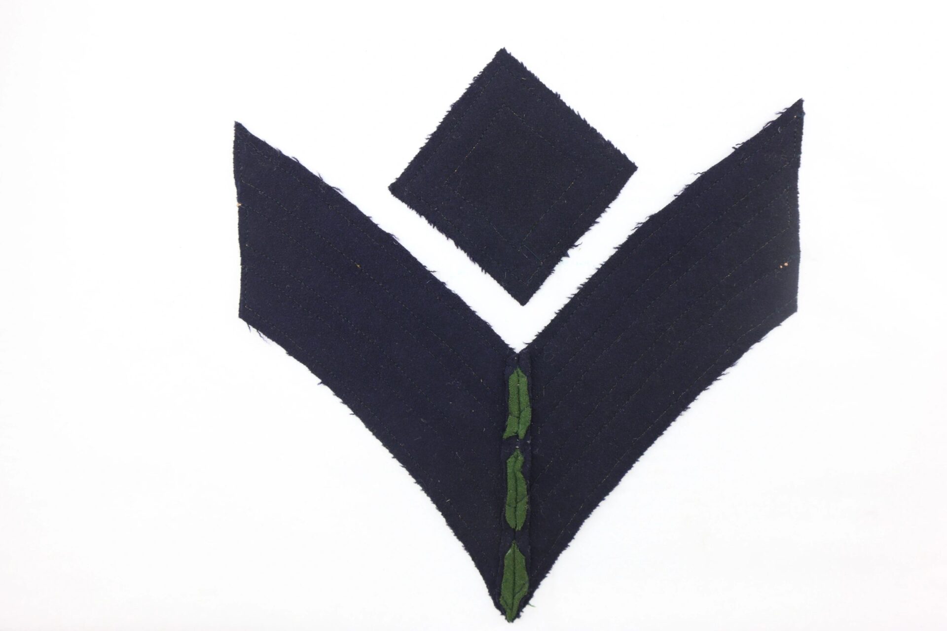 Two black fabric chevrons with a green center stripe, under a black diamond patch on white. Civil War Rifleman/Sharpshooter Chevrons / SOLD.