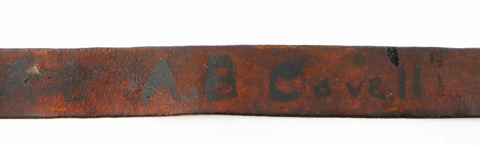 A U.S. Enlistedman’s belt marked “A.B. Covell,” featuring a worn brown leather strap with the name written in black marker.