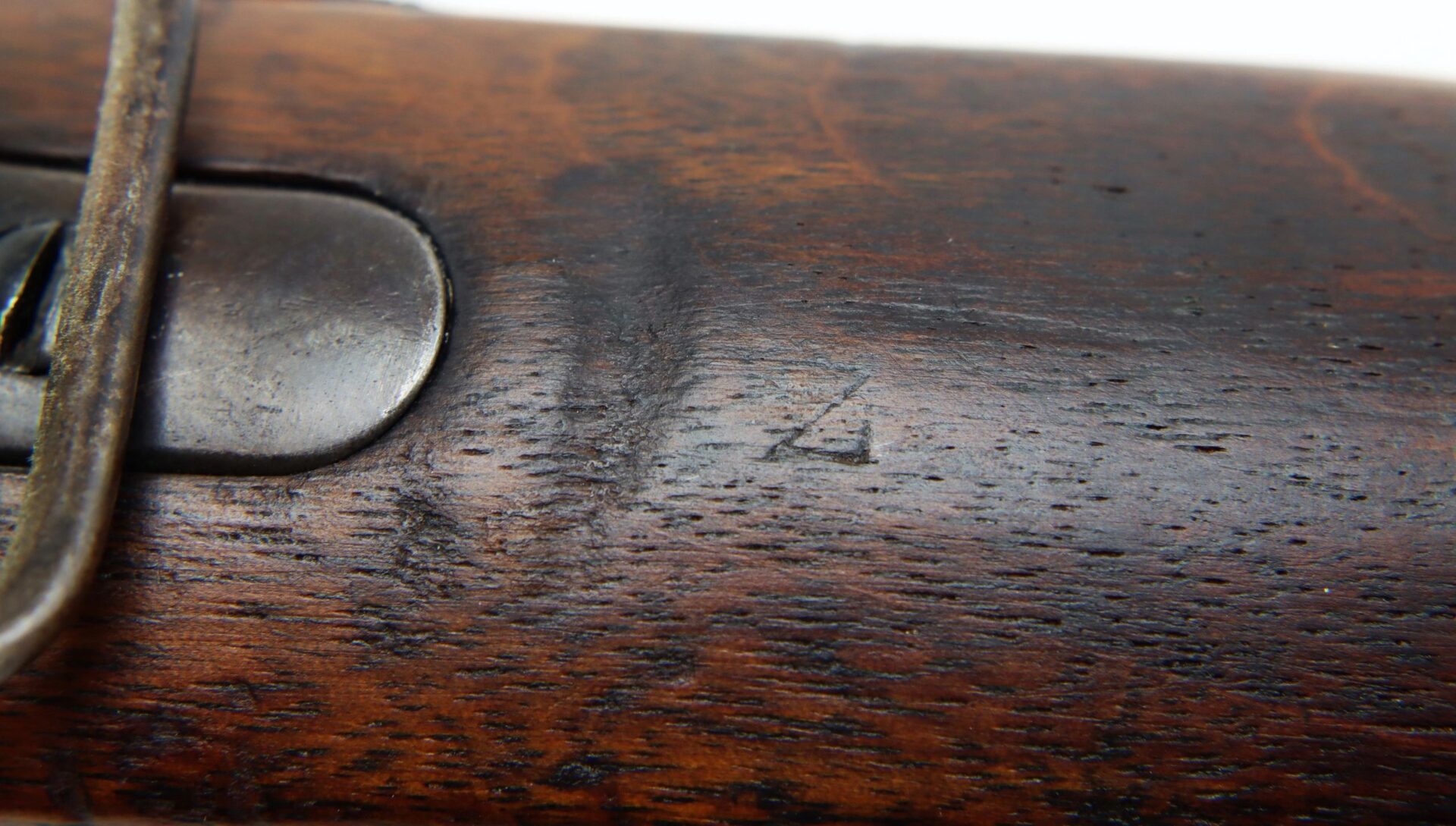 Close-up of the Confederate “Captured and Collected” Model 1861 Springfield Rifle-Musket's wooden stock, featuring a small engraved "Z" marking and partially visible metal hardware on the left side.