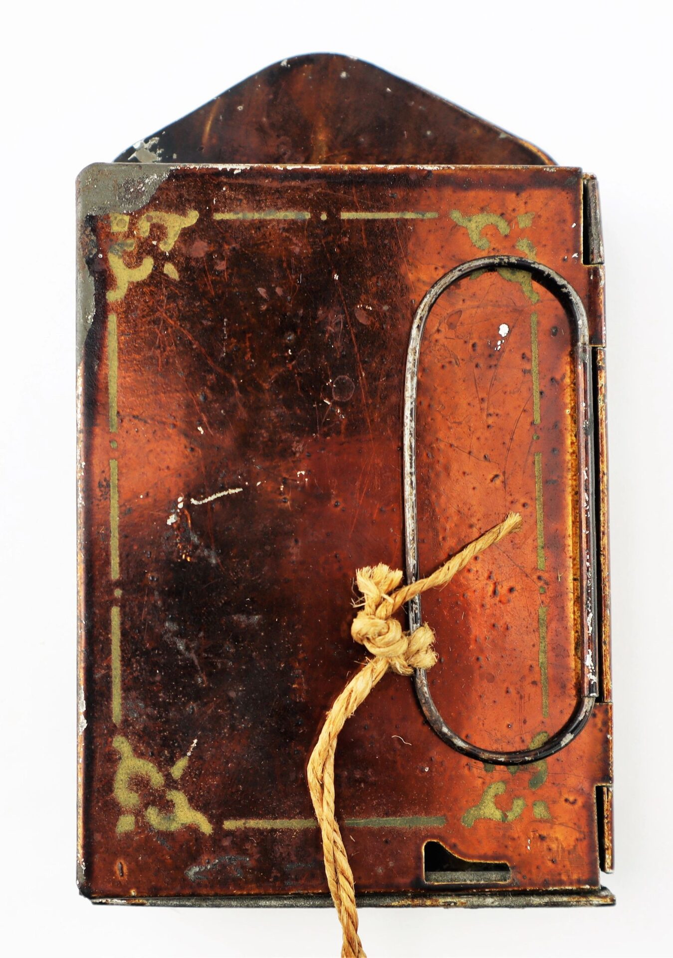 Civil War Era Minor’s Patent Lantern: Rectangular metal object with decorative border, hinged side, oval cutout, brown string loop at center, triangular top section. Photographed on a white background.