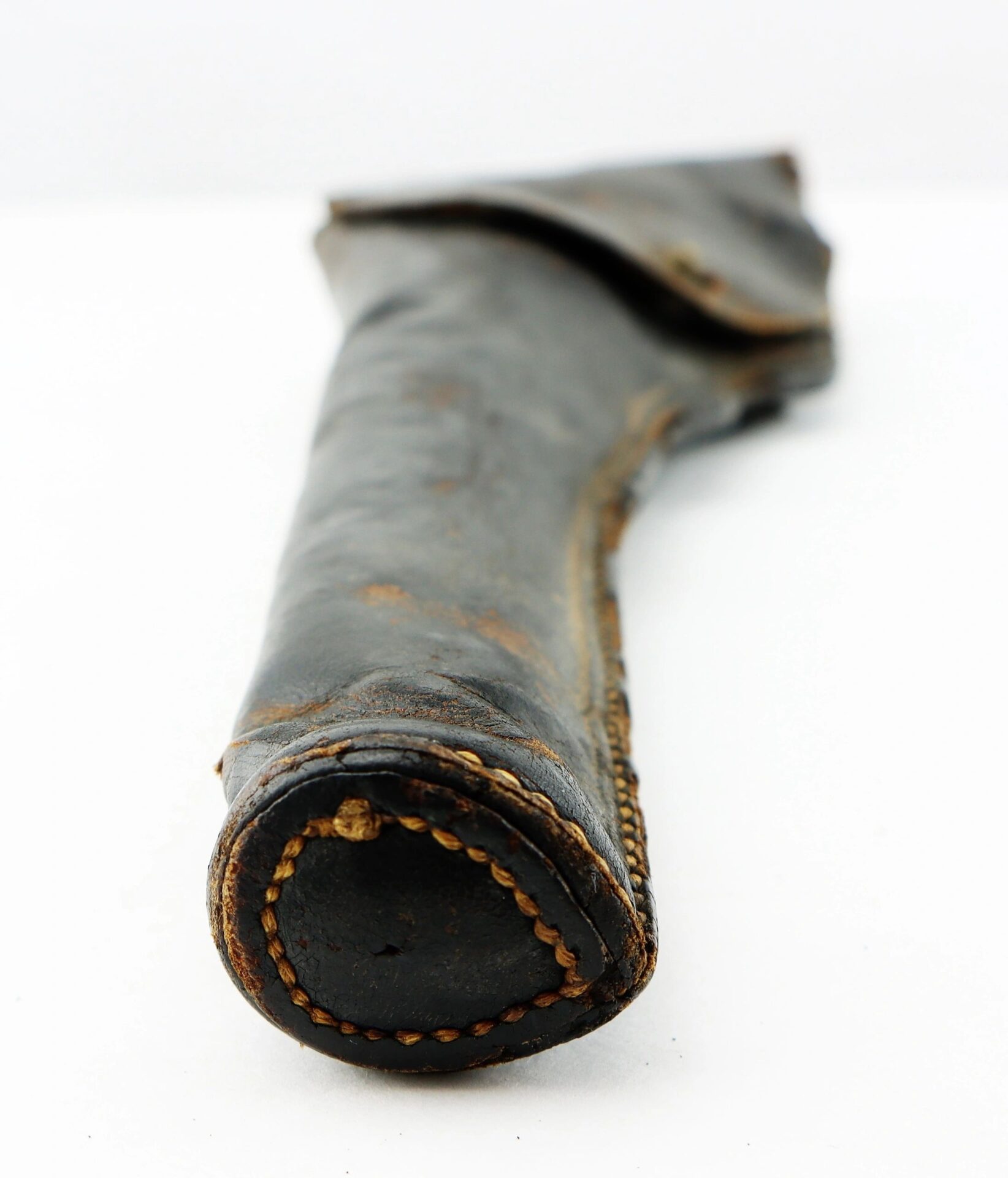 A close-up of a worn Civil War Era Revolver Holster made of black leather with visible stitching, laid on a white surface.