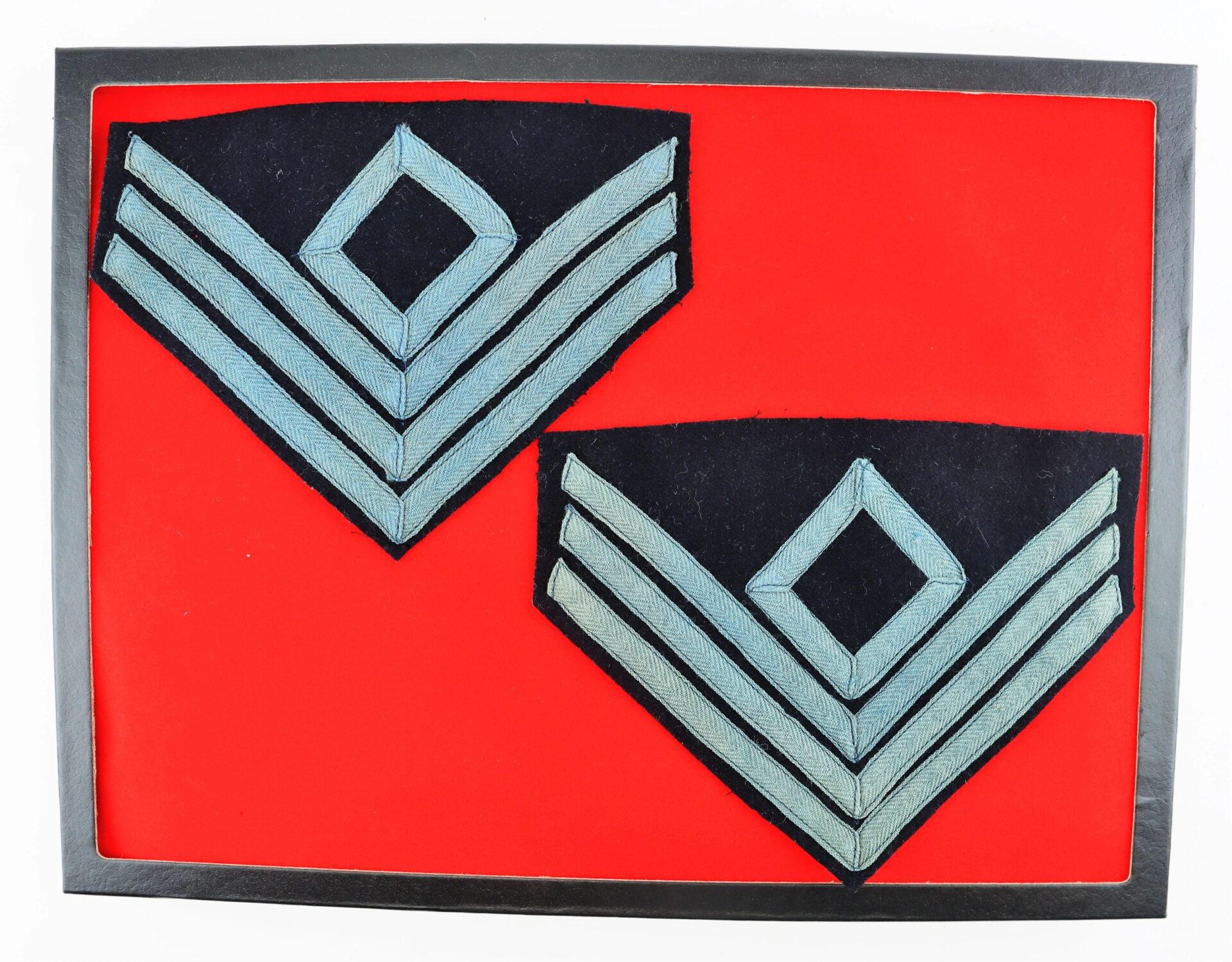 The First Sergeant of Infantry Chevron features two military chevrons with three stripes and a diamond above, set on a red background within a black frame.