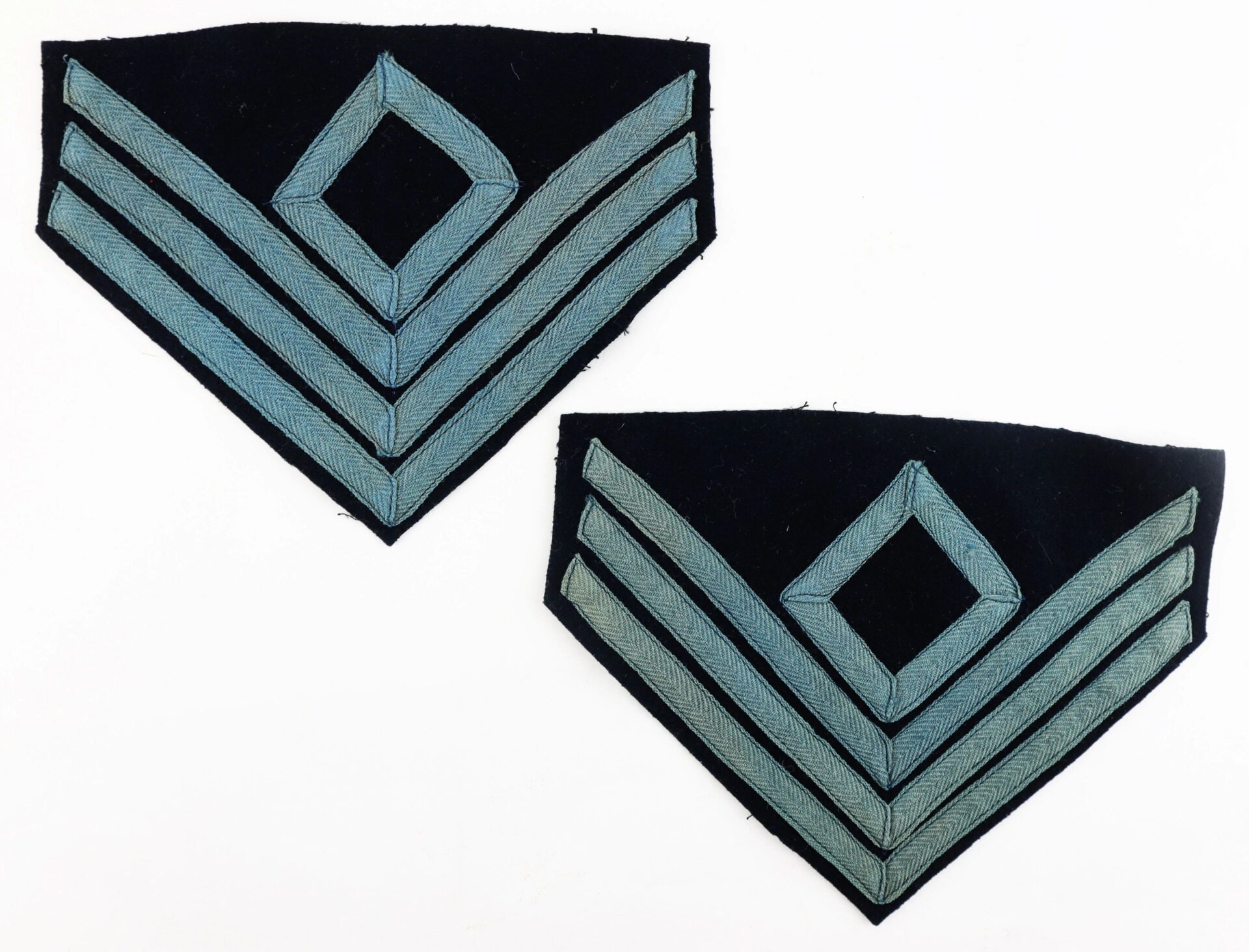 A pair of First Sergeant of Infantry Chevron patches, featuring three light blue stripes and a central diamond on dark fabric, are displayed on a white background.