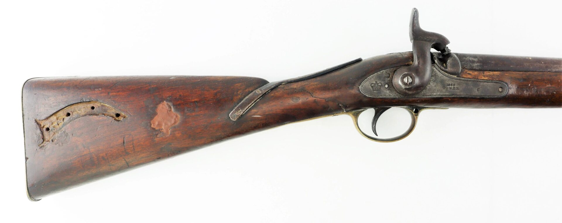 A Confederate 1863 dated Enfield, altered to a cavalry carbine, with a damaged wooden stock and visible metal firing mechanism, is displayed on a white background.