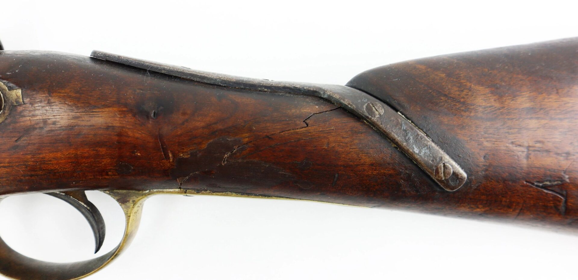 Close-up of the Confederate 1863 Dated Enfield, altered to a cavalry carbine, showing its wooden stock with a metal reinforcement plate and visible cracks near the trigger guard.